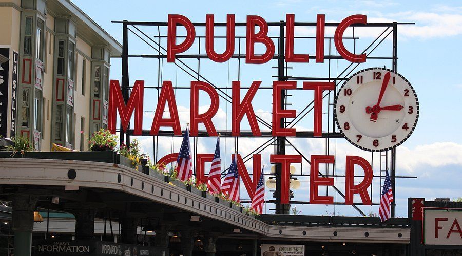 A sign for the public market center with a clock on it