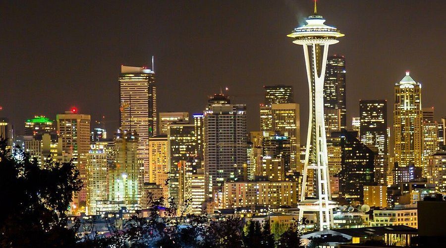 A city skyline at night with the space needle in the foreground