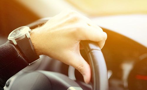 A close up of a person 's hand on the steering wheel of a car.