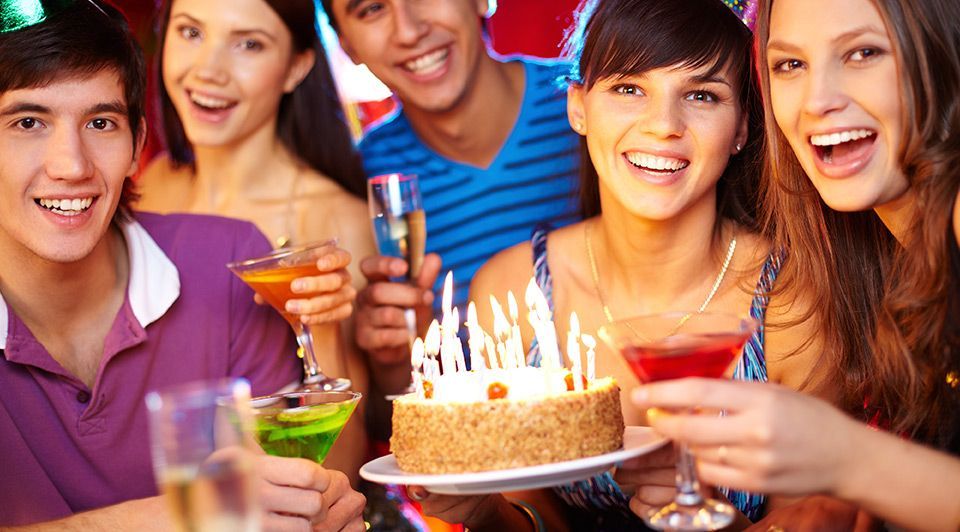 A group of people are celebrating a birthday with a cake and drinks.