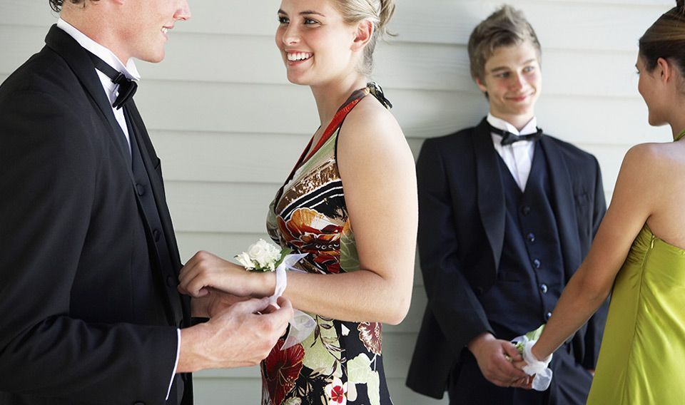 A woman in a green dress is standing next to a man in a tuxedo