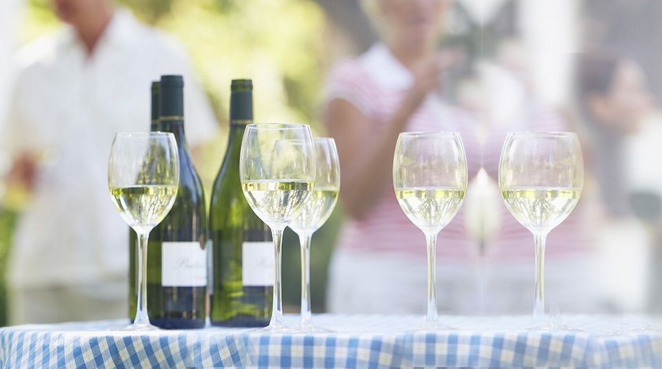 A bottle of wine and three glasses of wine are on a table.