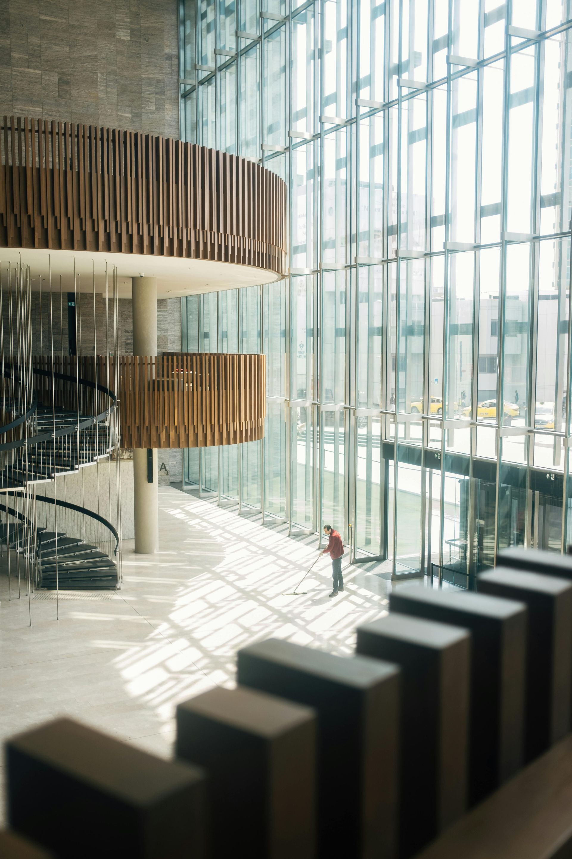 A man in a red jacket is standing in a lobby of a building.