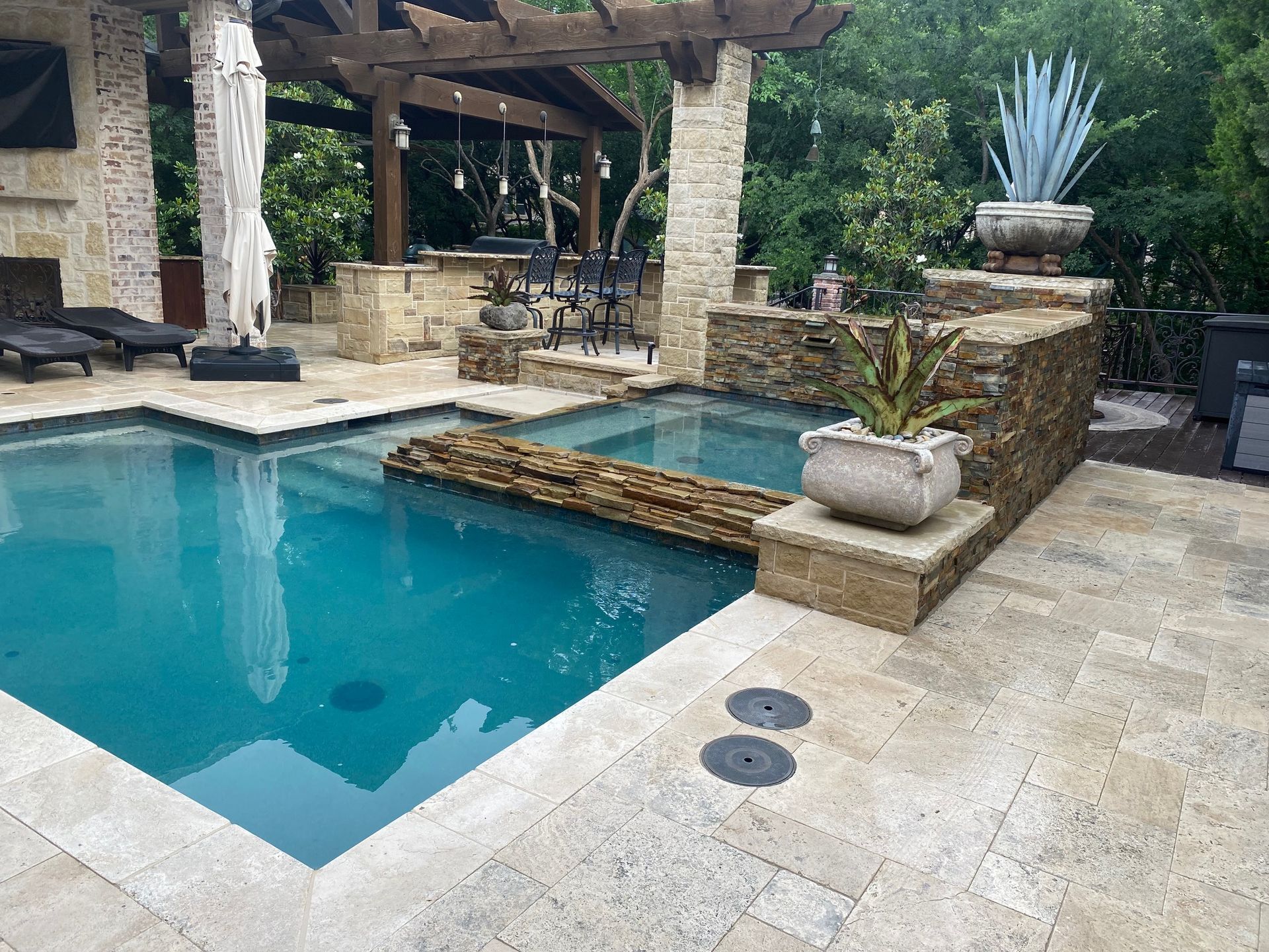 A large swimming pool is surrounded by a stone patio.