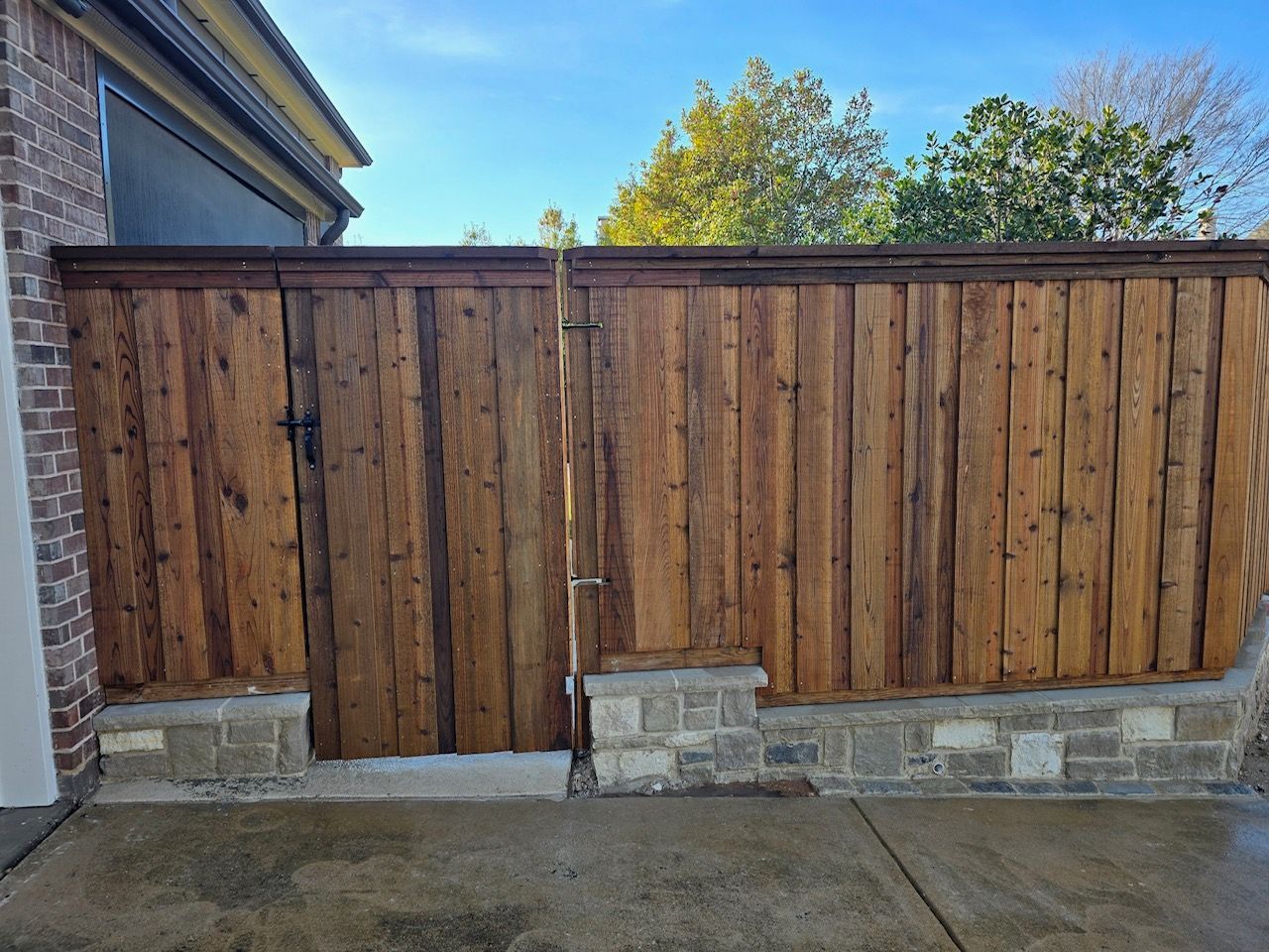 A wooden fence is sitting next to a brick building.