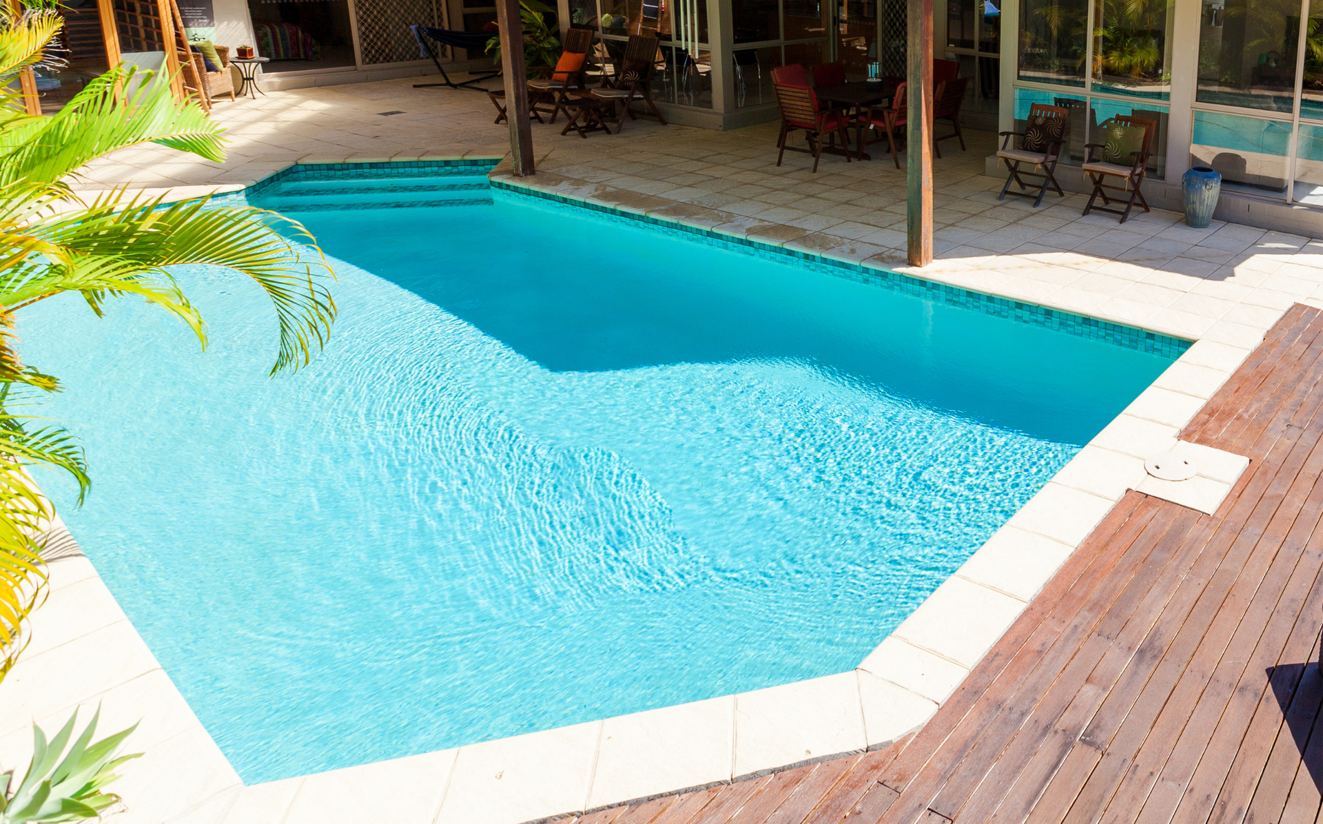 A large swimming pool with a wooden deck in front of it