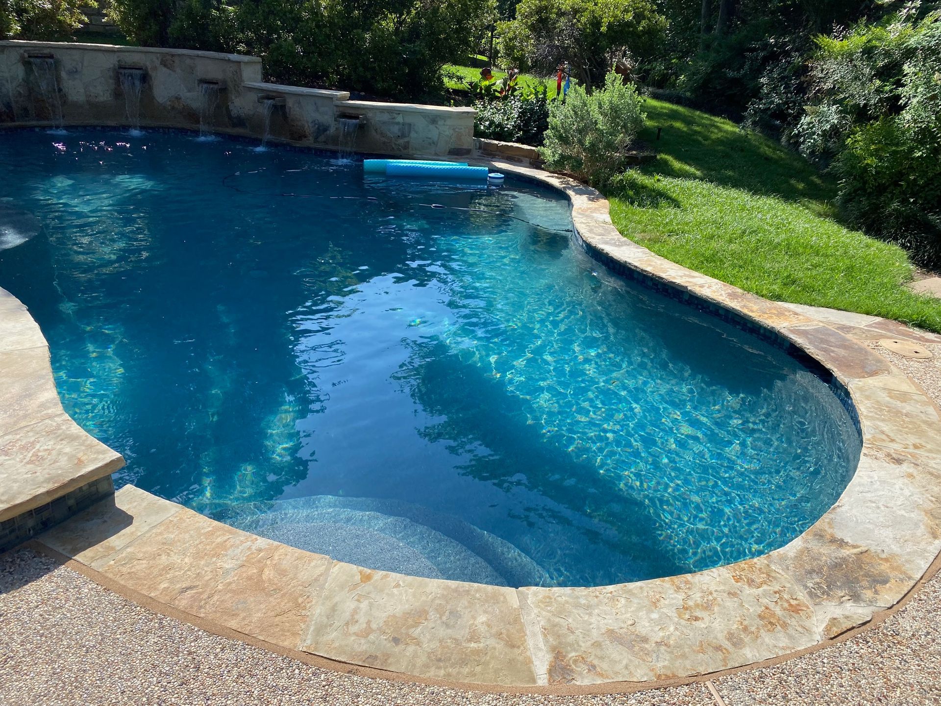 A large swimming pool surrounded by grass and trees