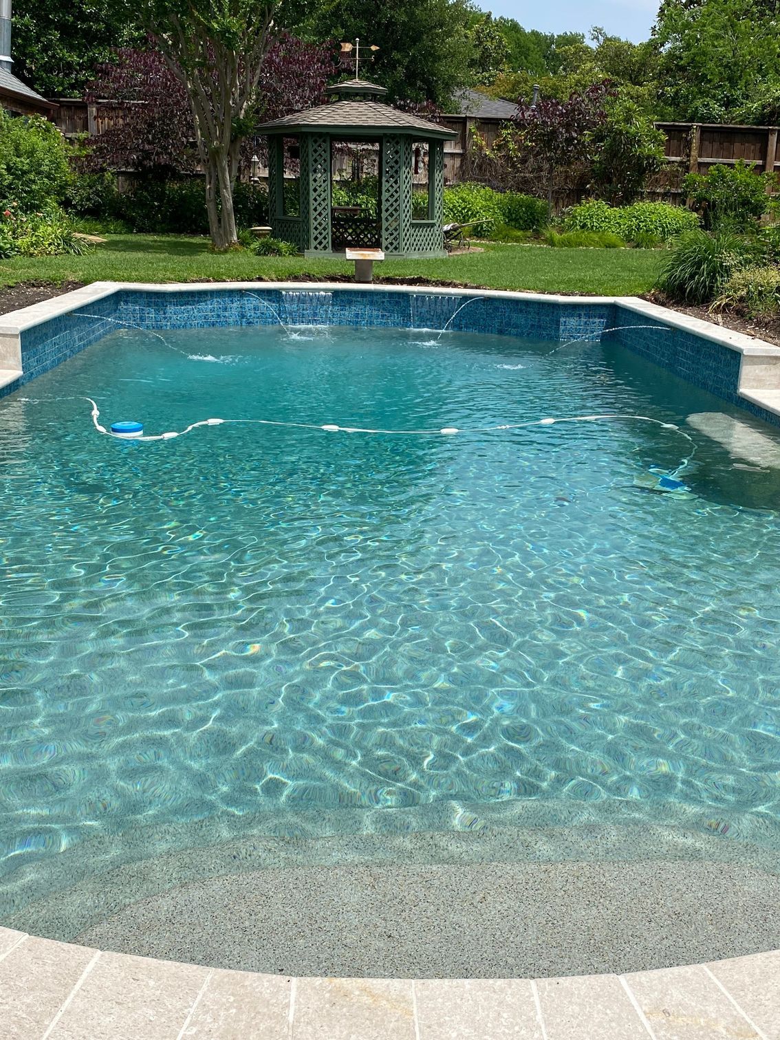 A large swimming pool with a gazebo in the background.