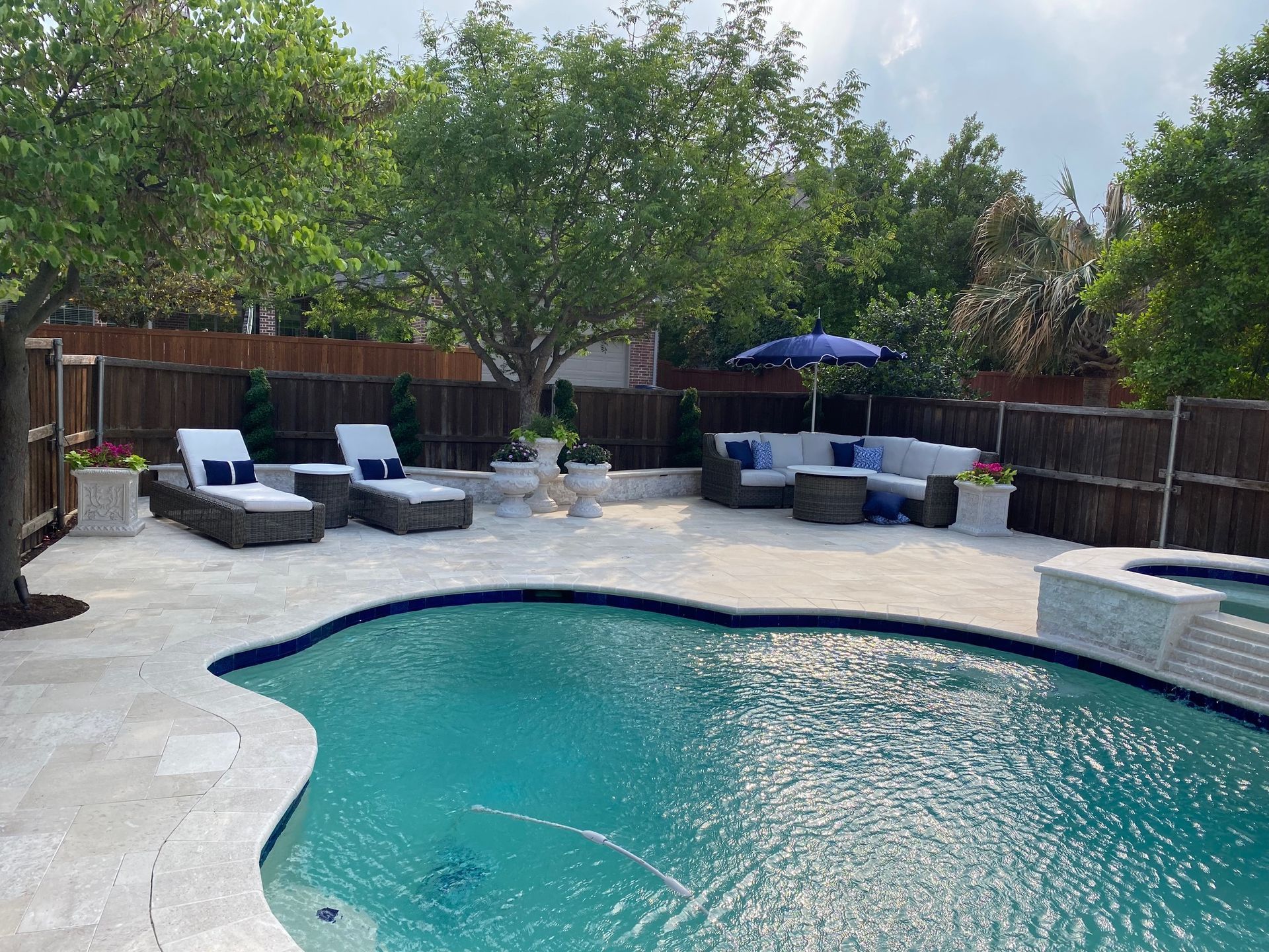A large swimming pool surrounded by chairs and umbrellas in a backyard.