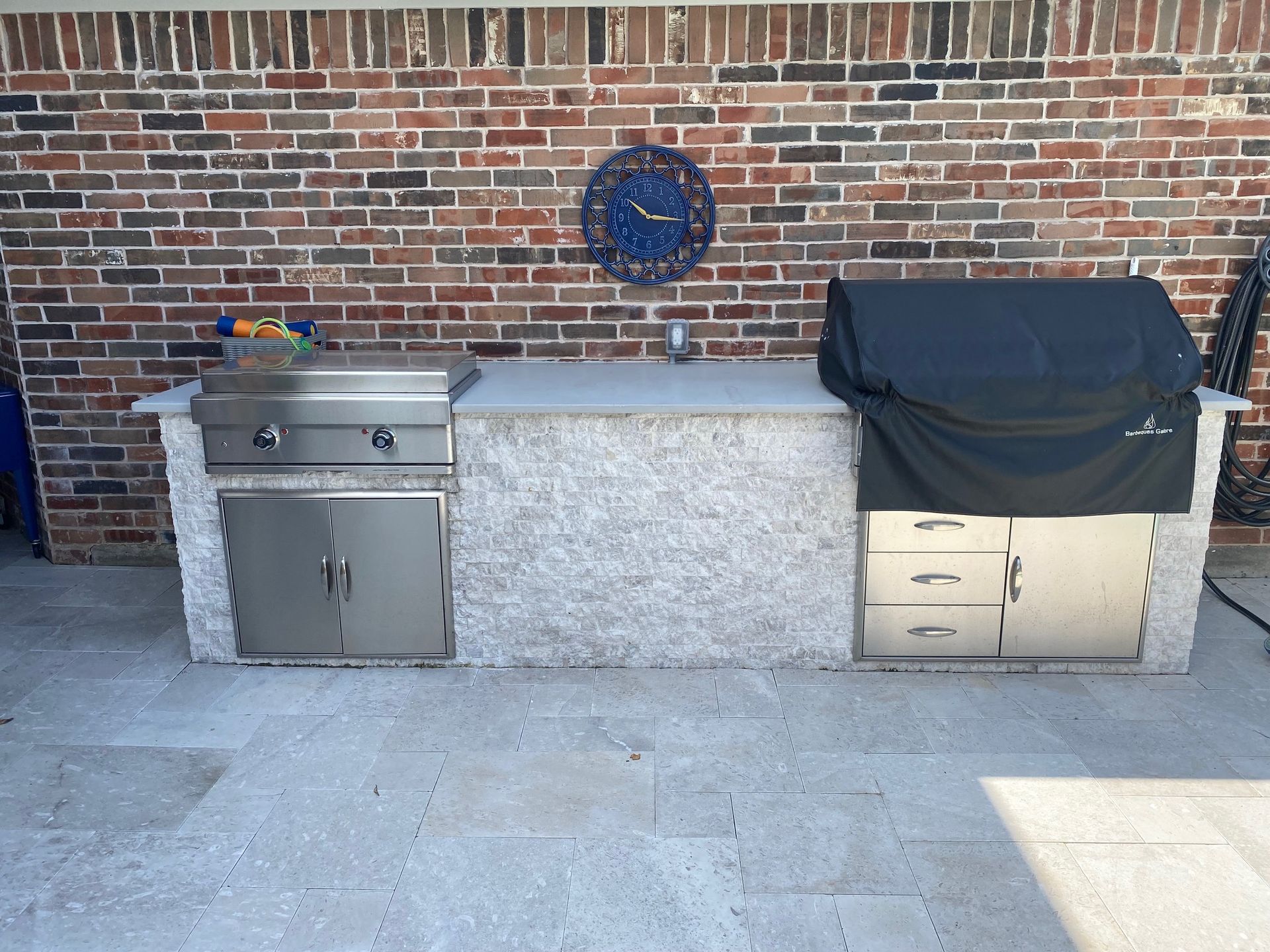 A brick wall with a clock above a grill
