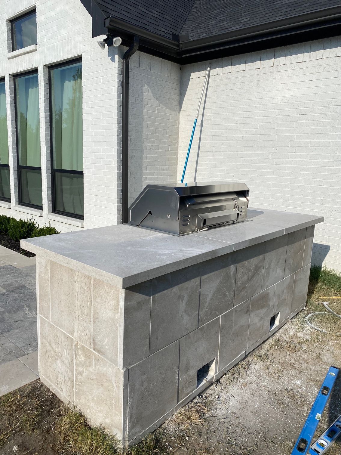 A grill is sitting on top of a concrete block in front of a house.