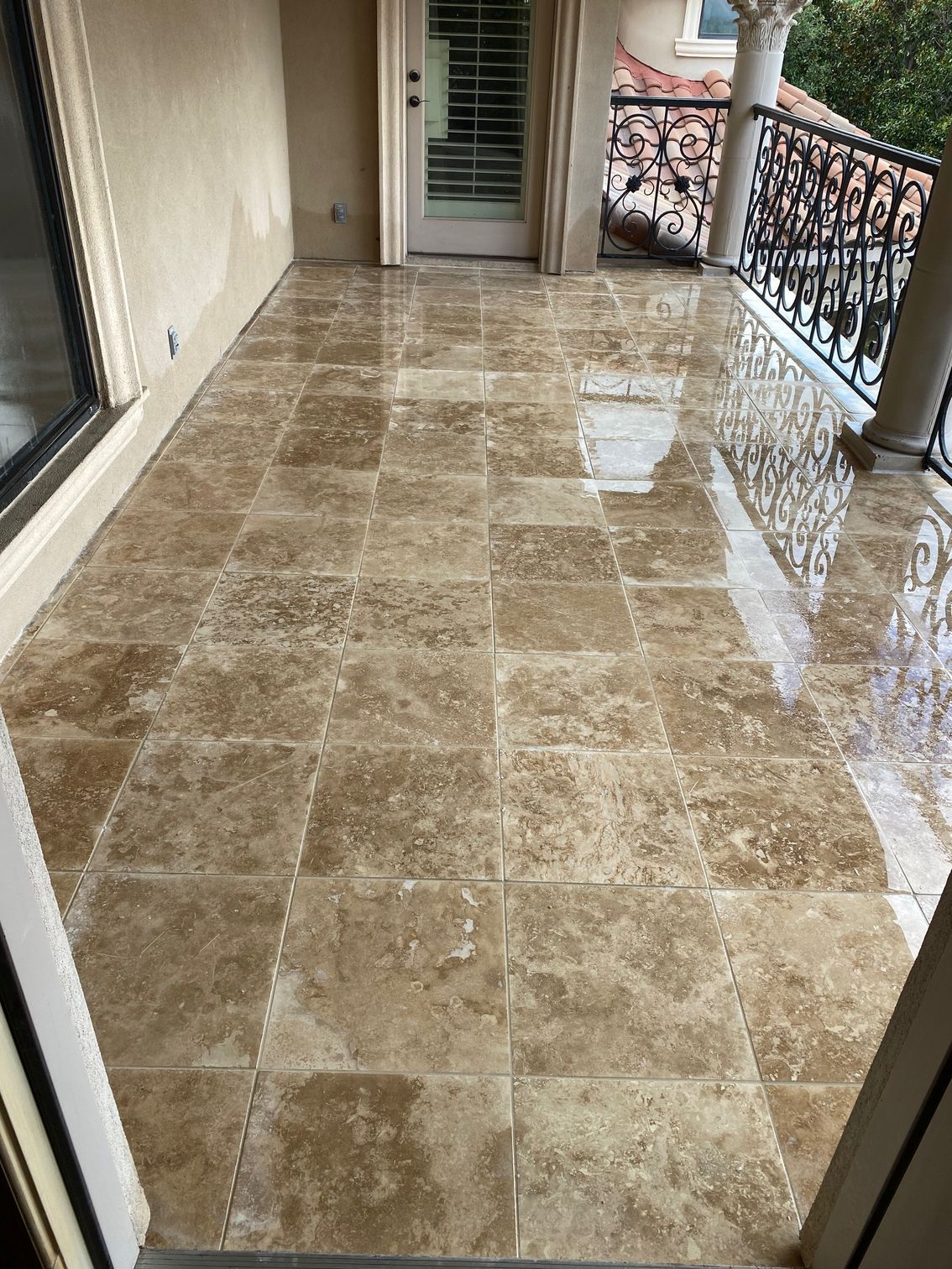 A tiled floor on a balcony with a wrought iron railing.