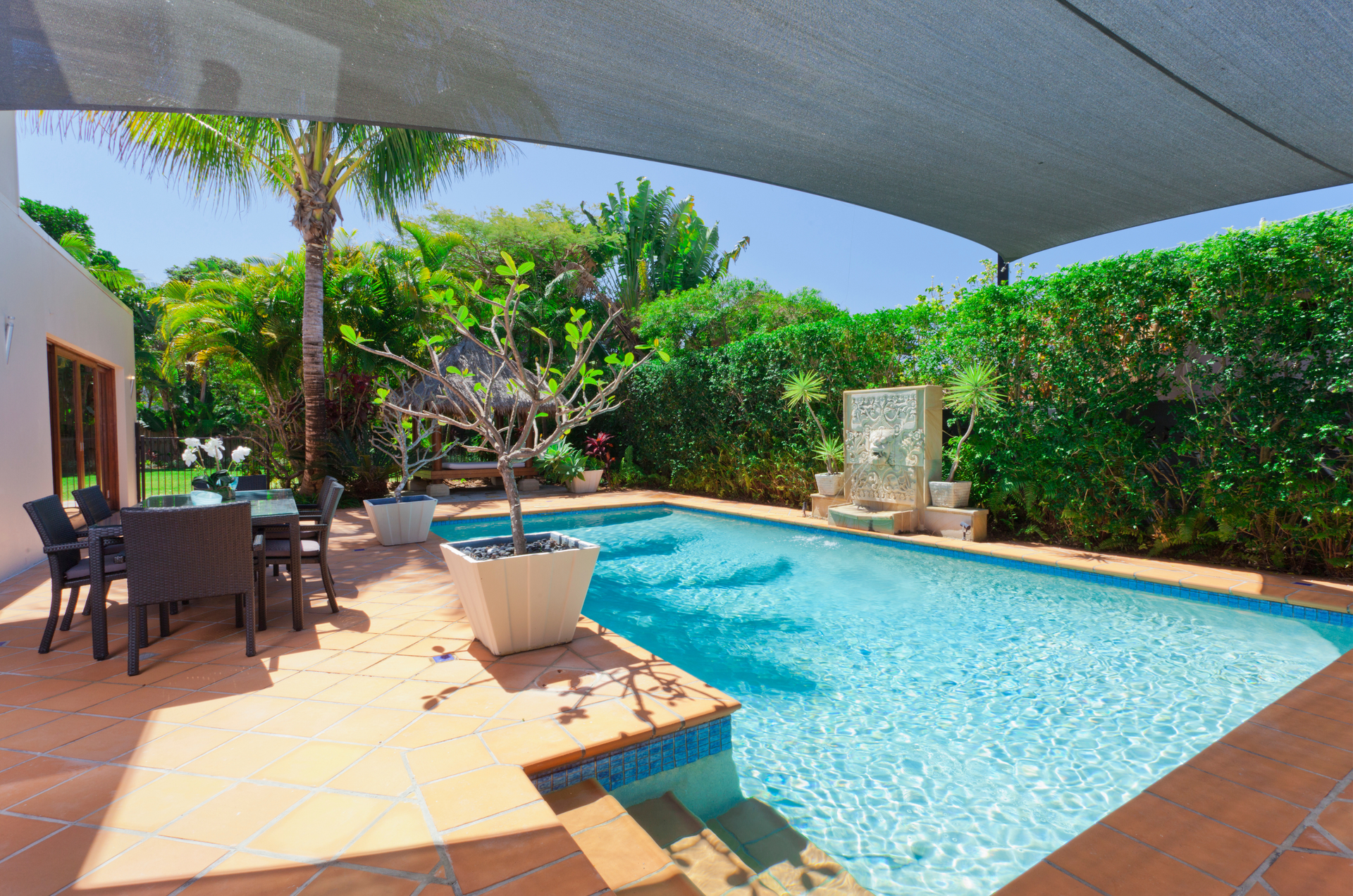 A large swimming pool is surrounded by a patio with a table and chairs.