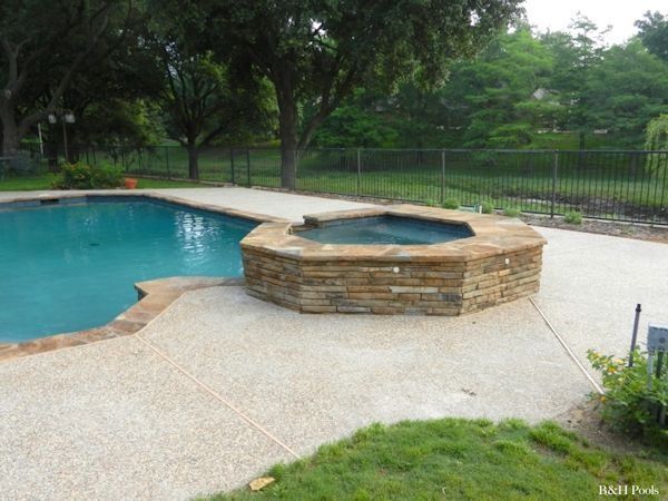 A swimming pool with a stone spa in the middle