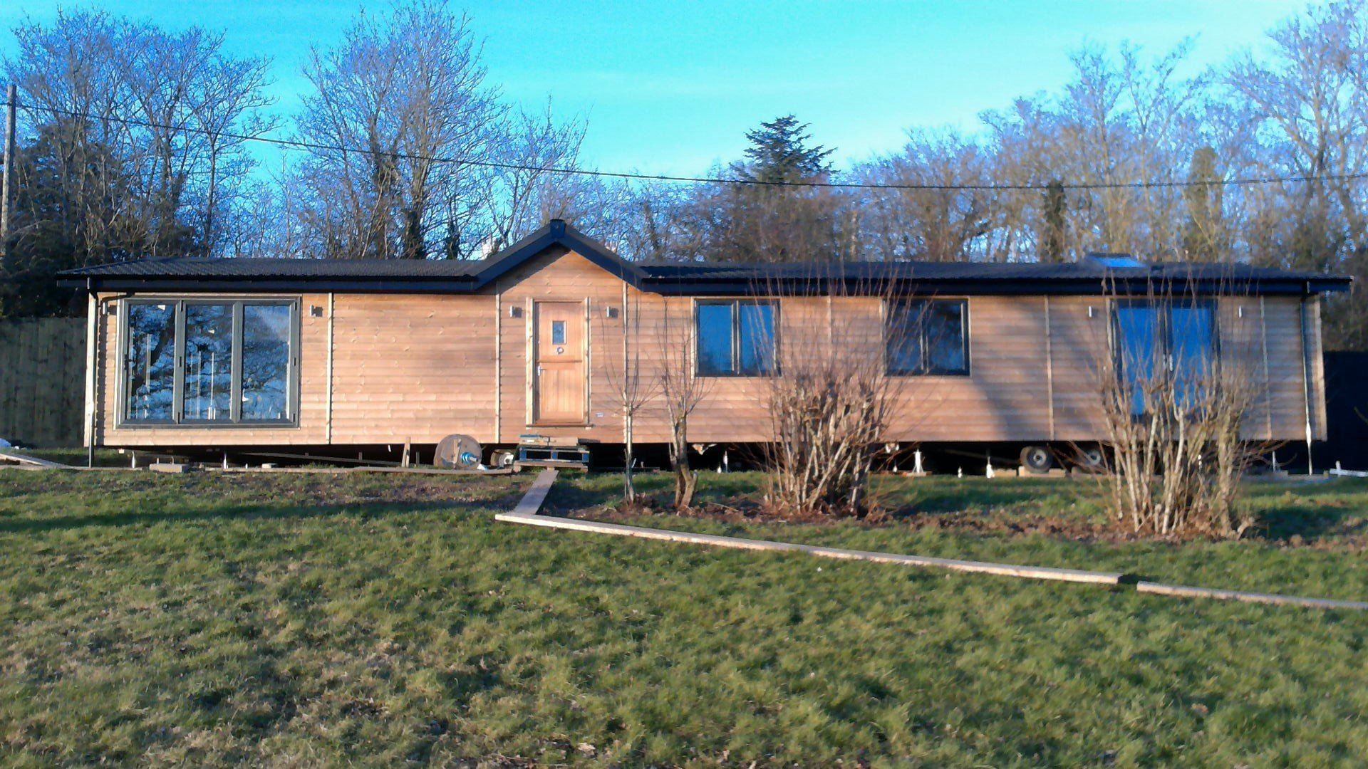 A large wooden house is sitting in the middle of a grassy field.