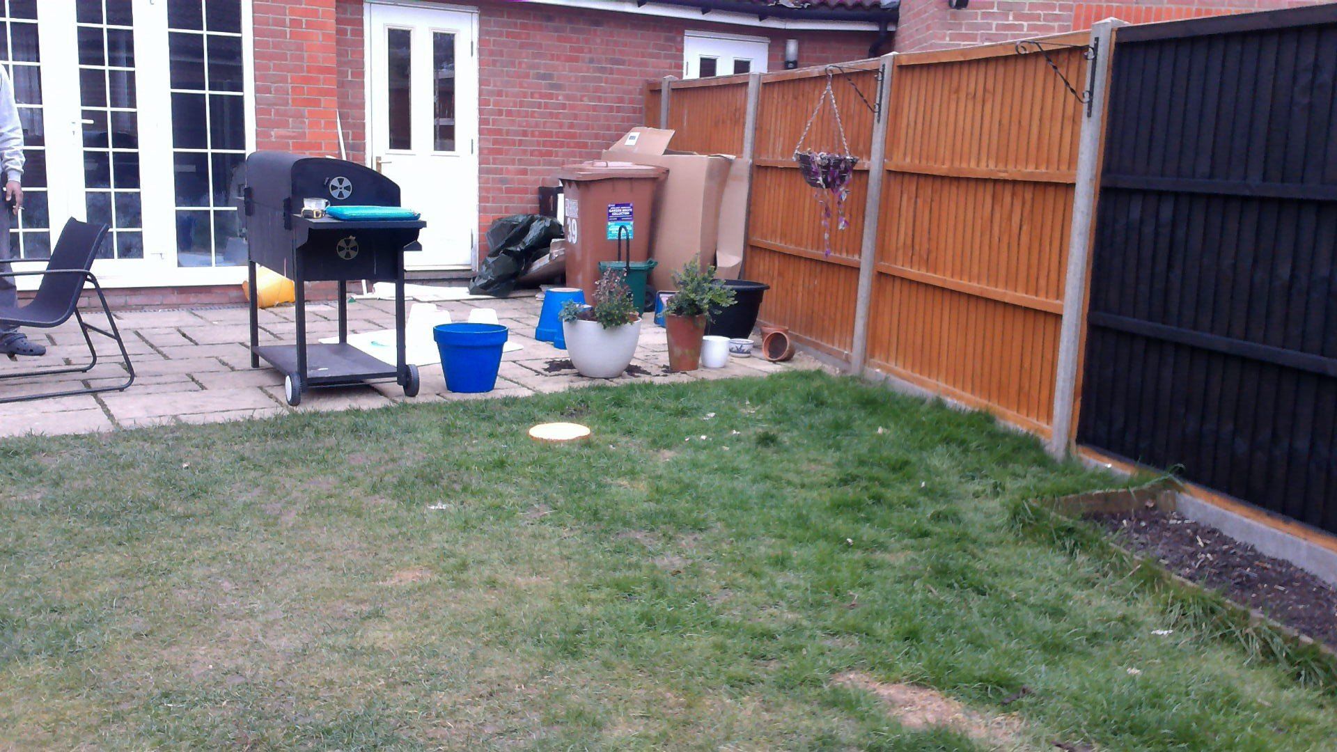 A backyard with a wooden fence and a grill