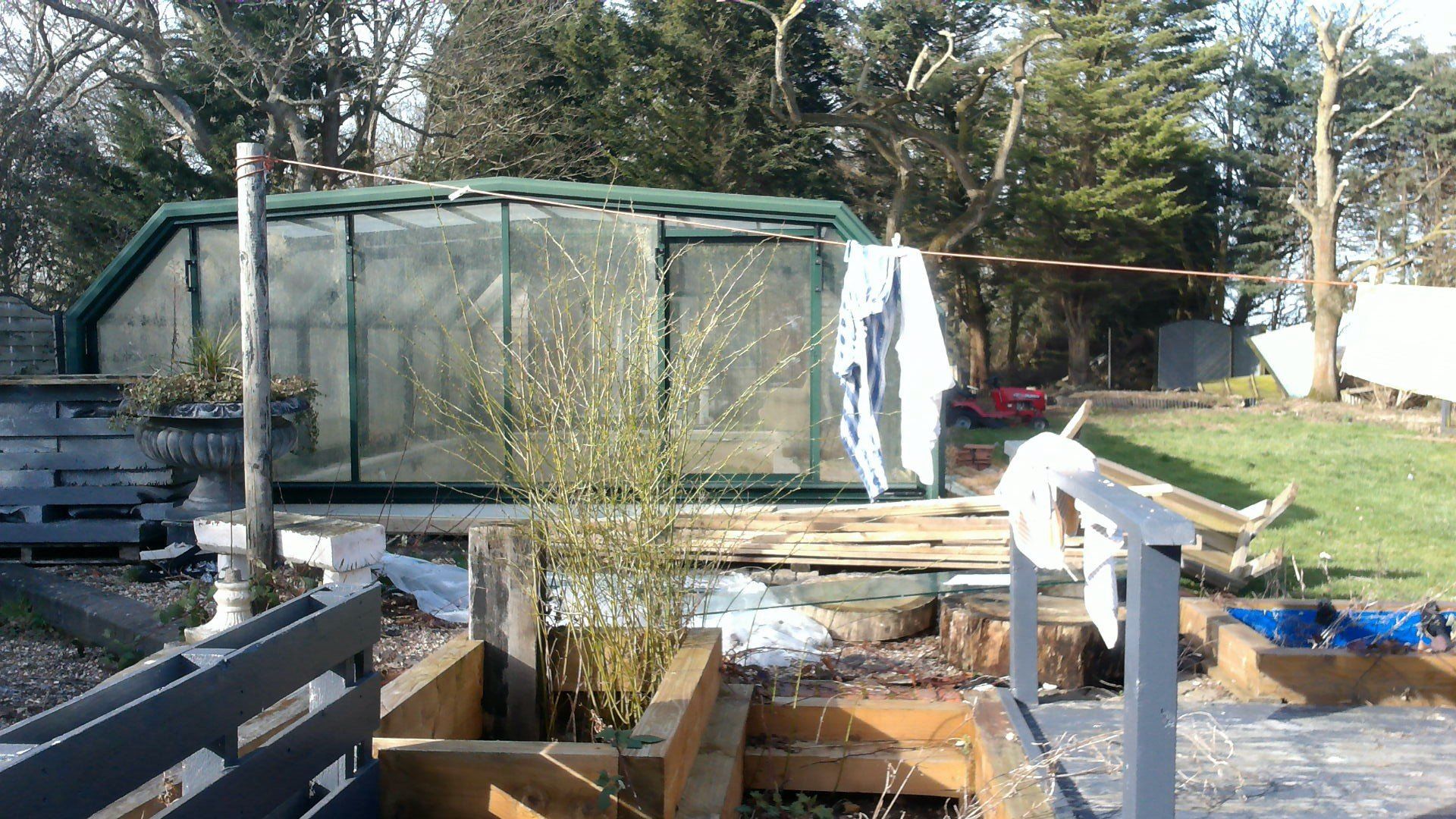 A greenhouse is being built in a backyard with trees in the background