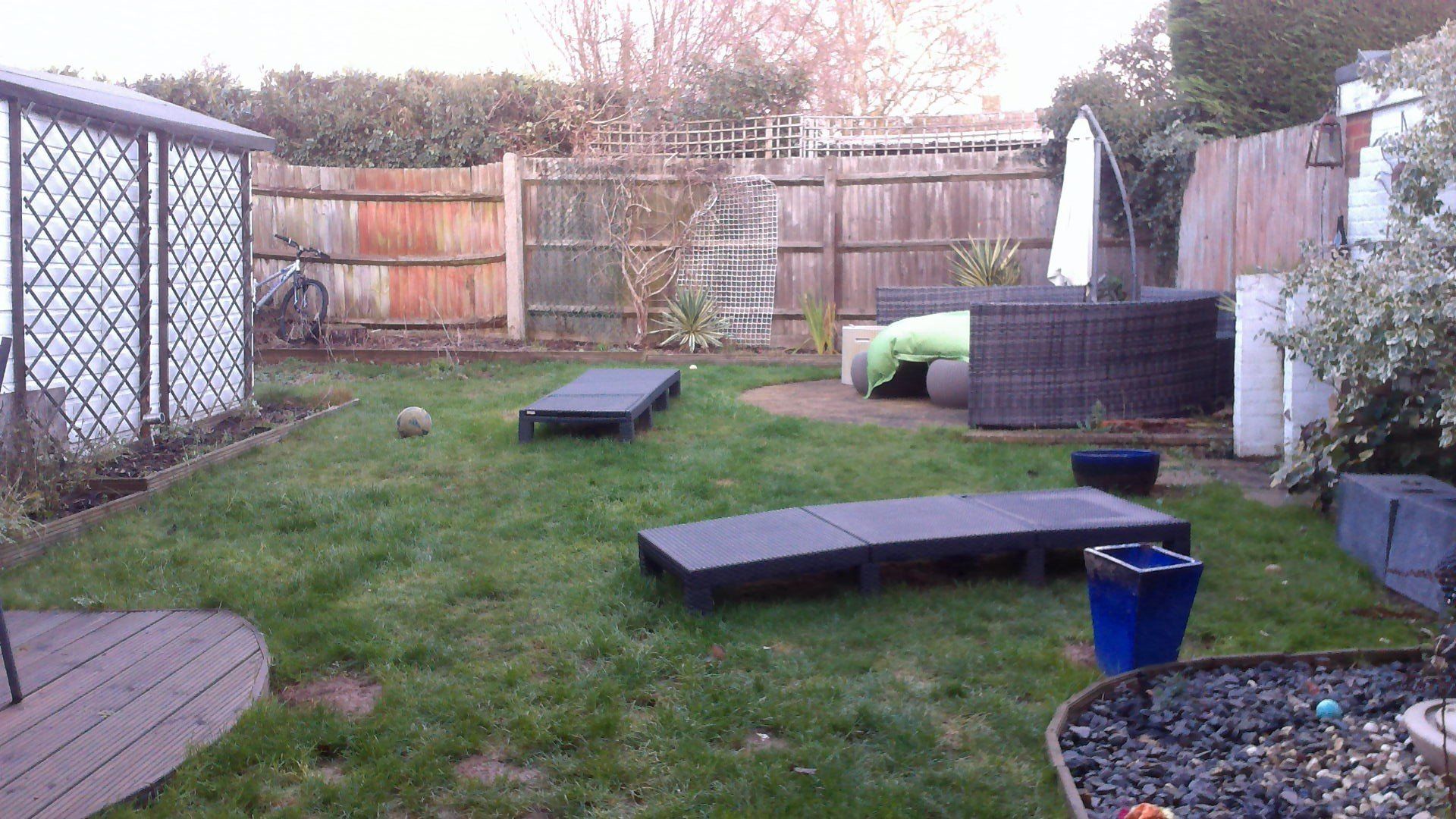 A backyard with a wooden fence and a lot of grass