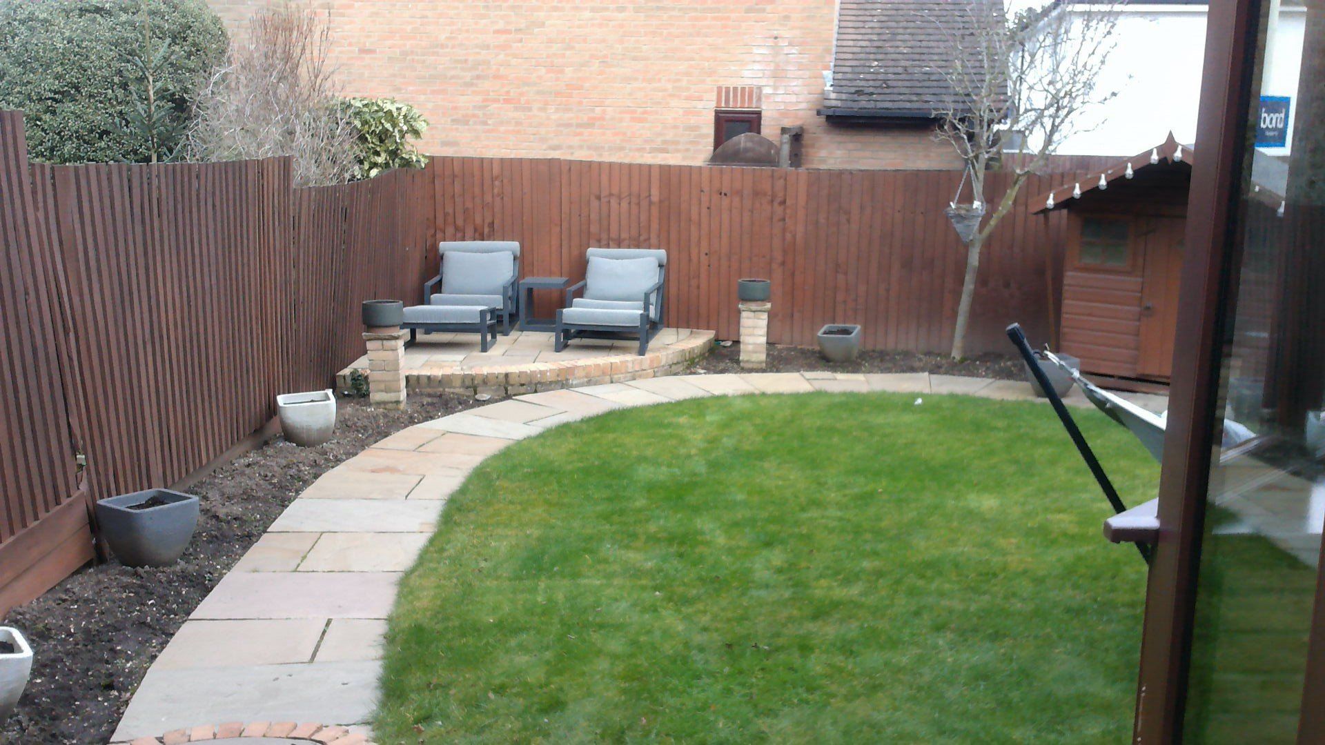 A backyard with a wooden fence and chairs