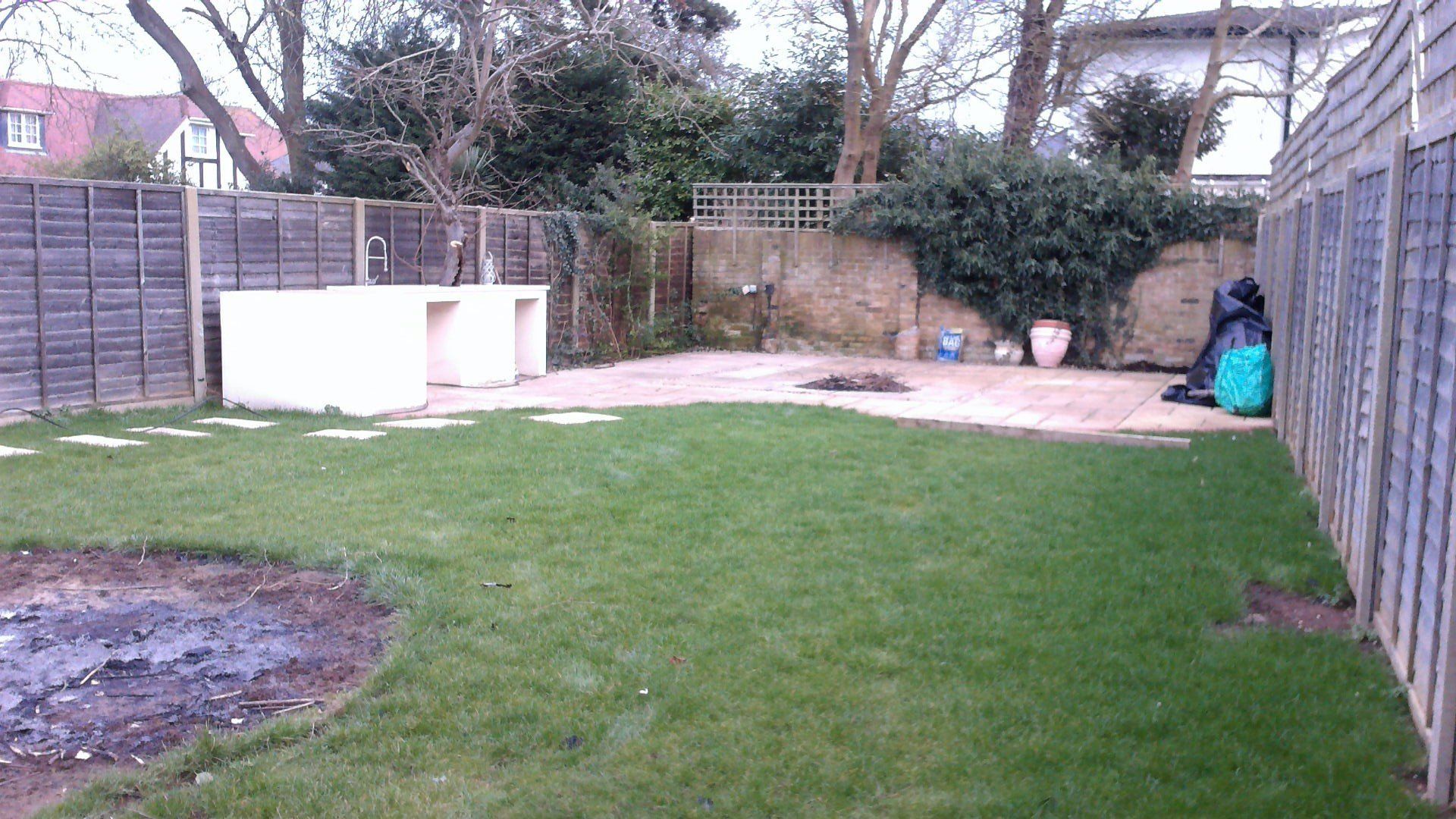 A fenced in backyard with a lush green lawn