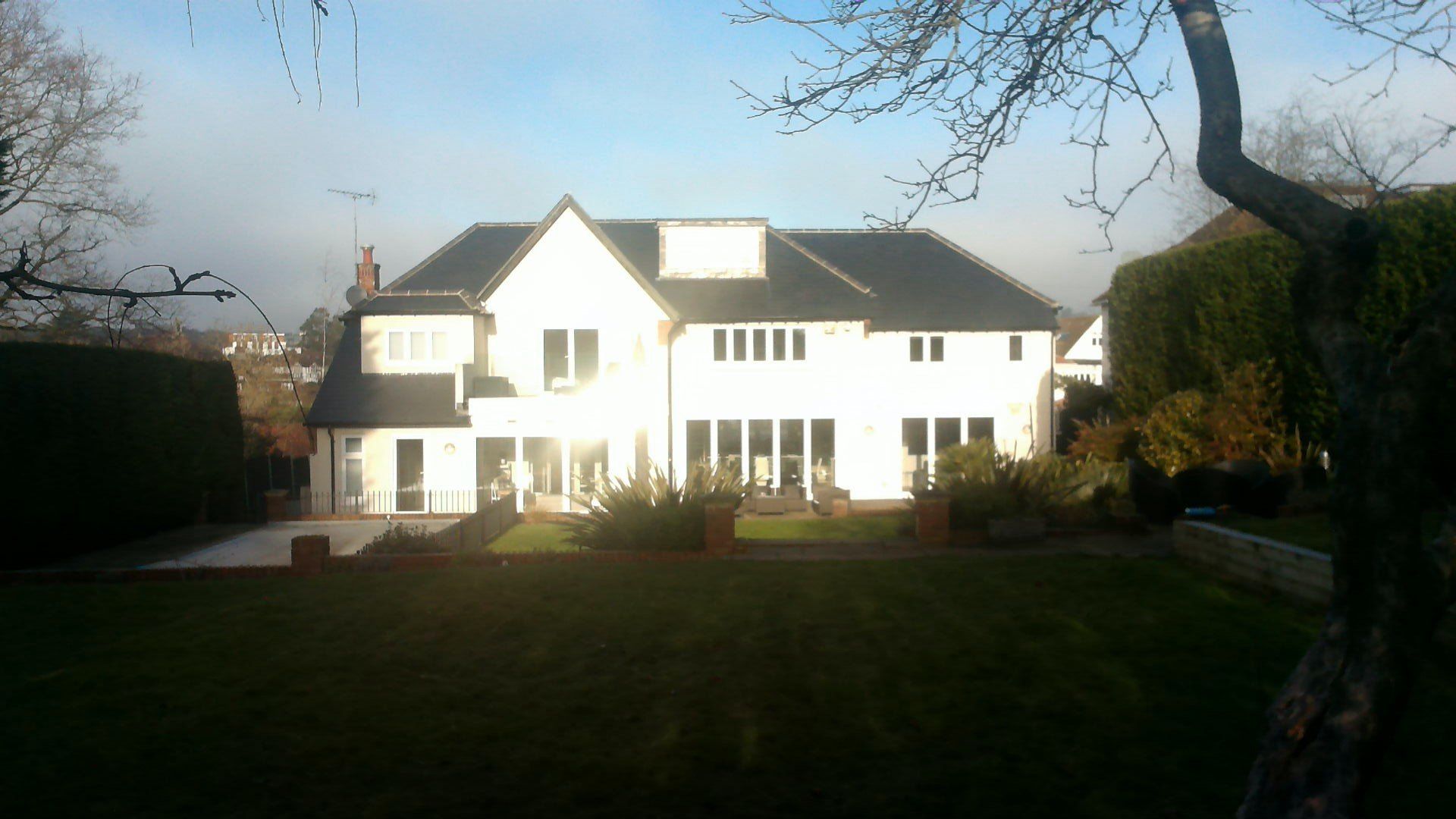 A large white house with a black roof is surrounded by trees