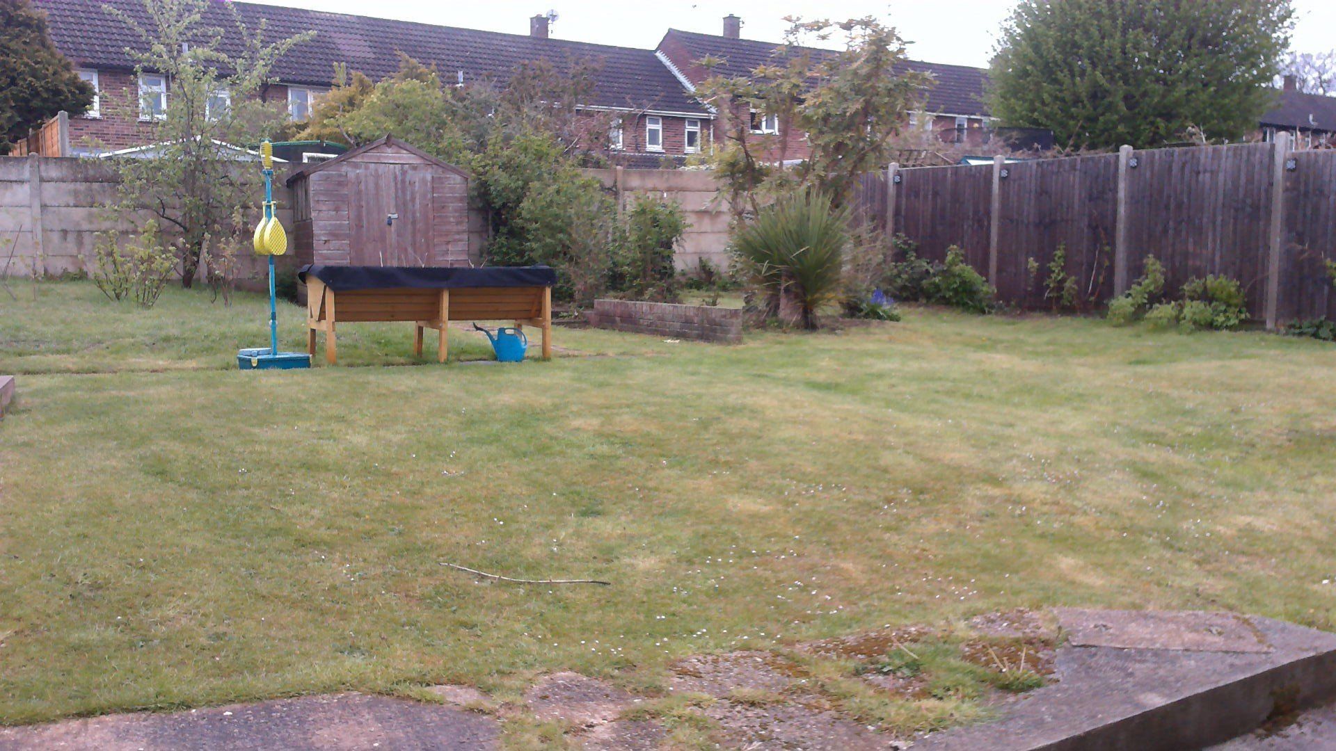 A backyard with a wooden table and a watering can