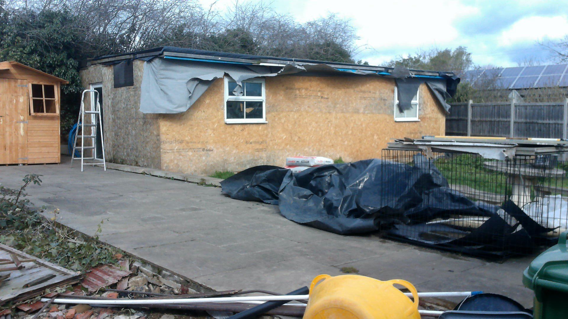 A yellow bucket sits on the ground in front of a house