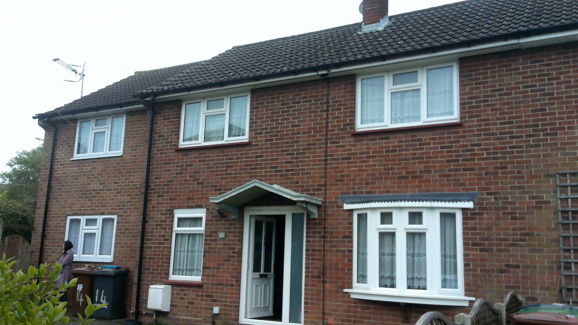 A red brick house with white windows and a black roof.