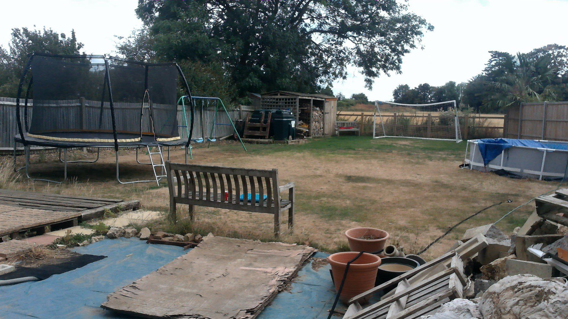 A backyard with a trampoline and a bench