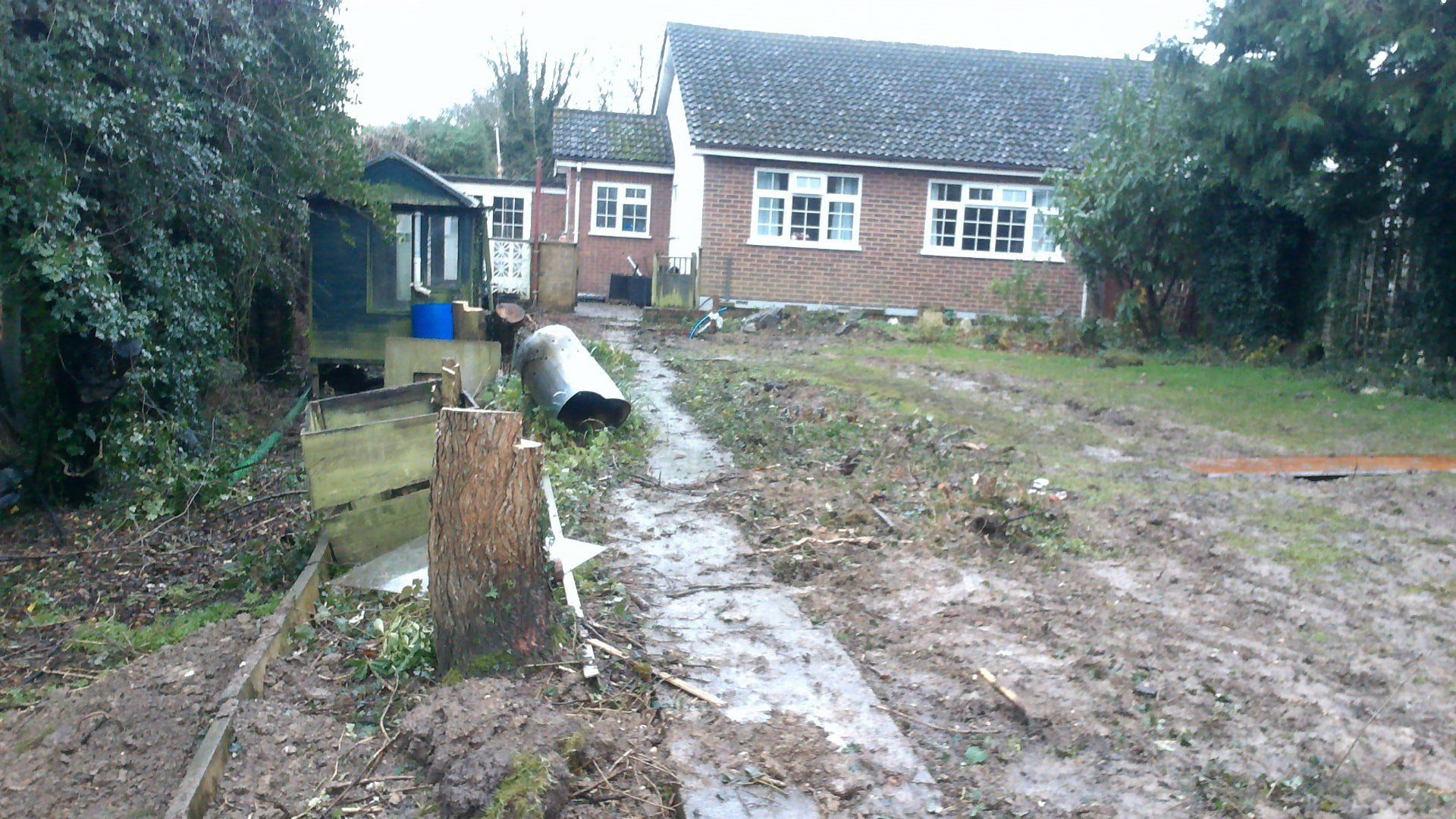 A brick house sits in the middle of a muddy yard