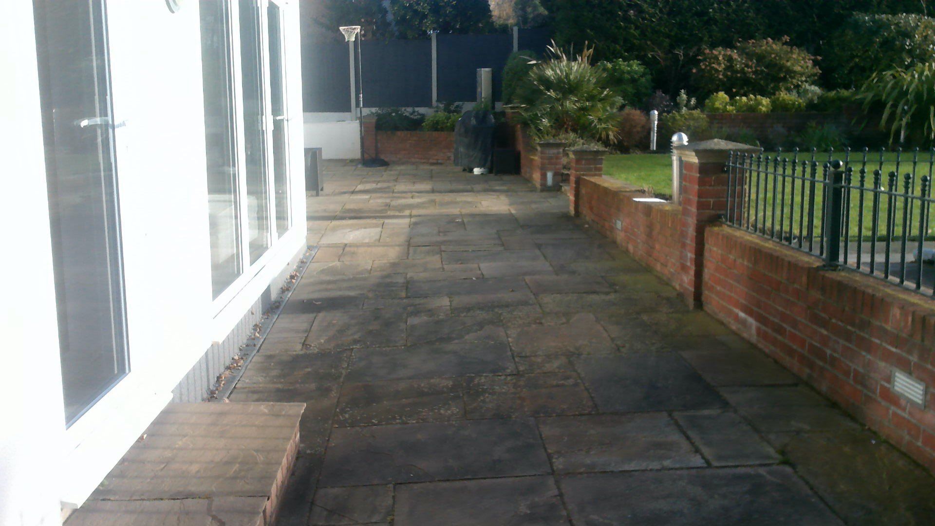 A brick walkway leading to a white building with a fence in the background.