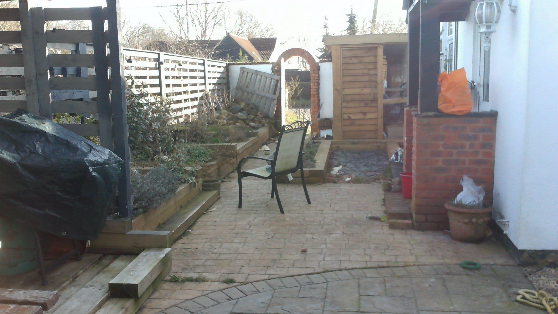 A patio with a chair and a fence in the background