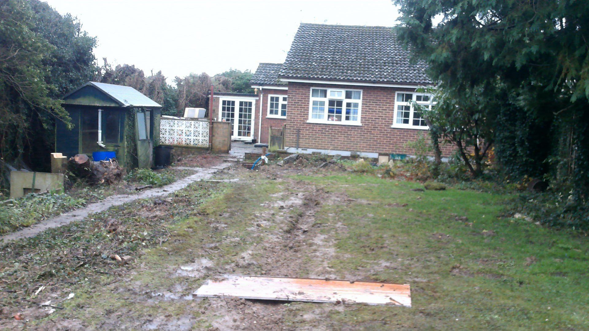 A brick house with a muddy driveway leading to it