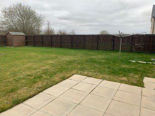 A backyard with a wooden fence and a patio.