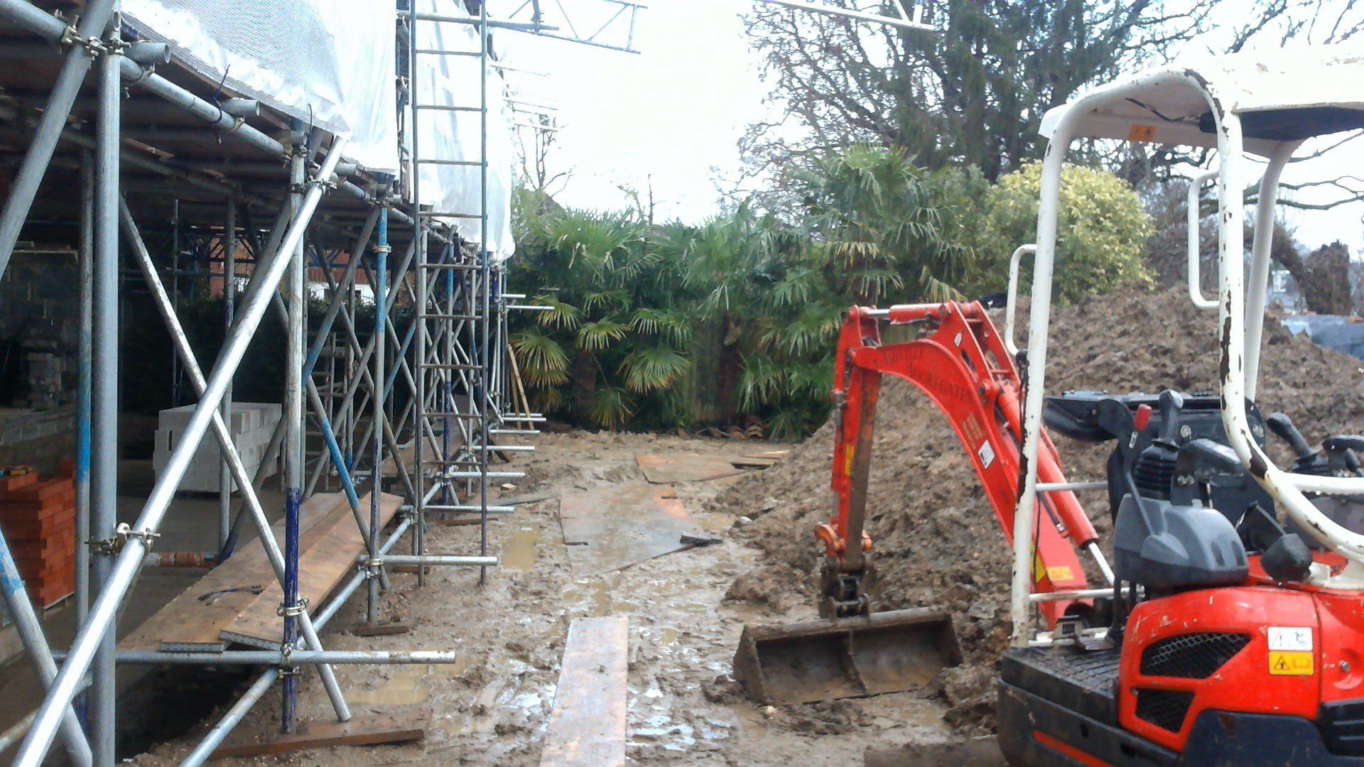 A small red excavator is digging a hole in the dirt.