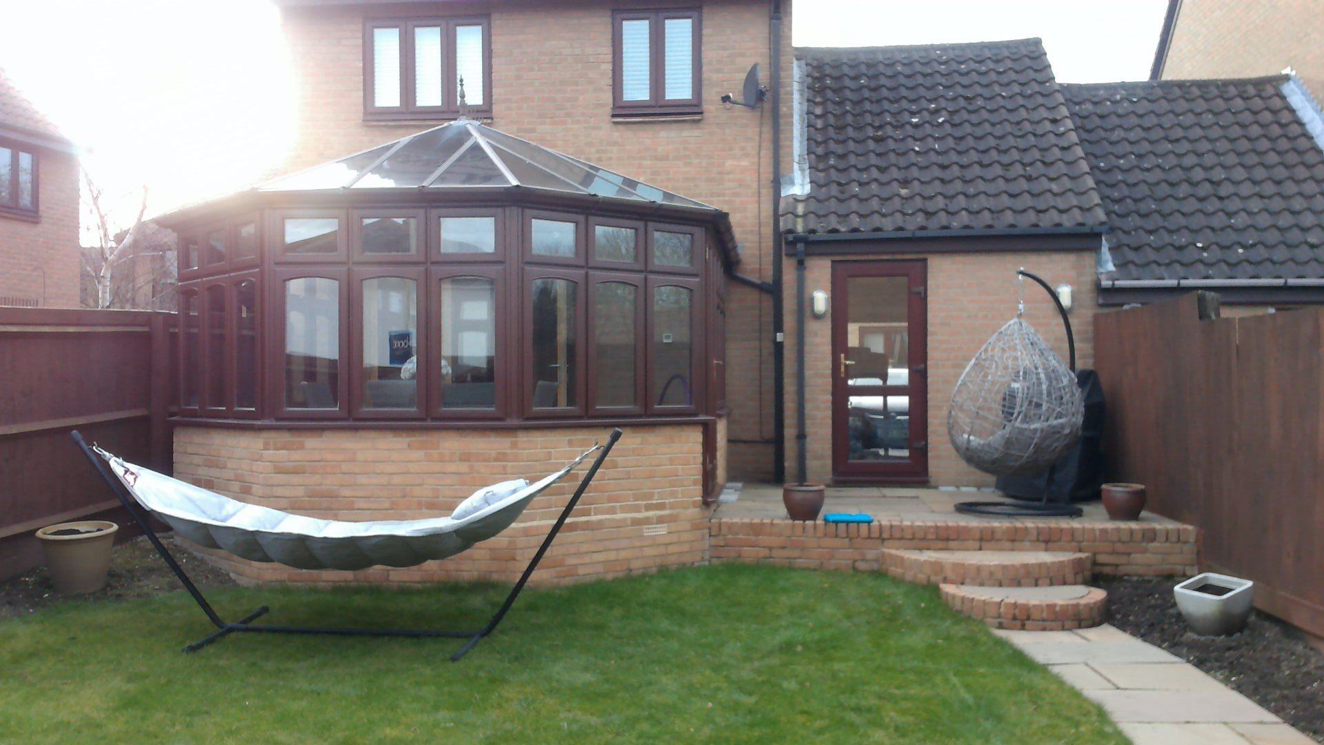 A hammock is sitting in a garden in front of a house.