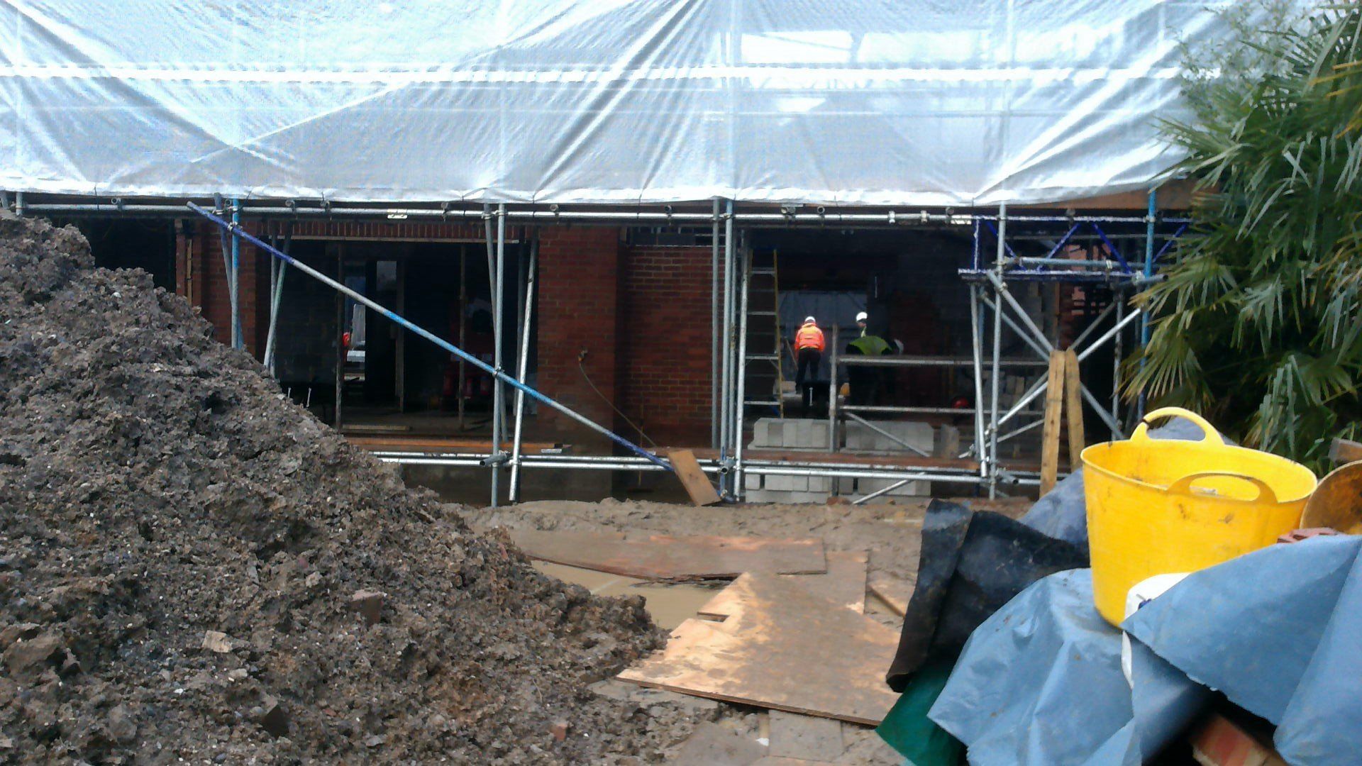 A large pile of dirt is in front of a building under construction