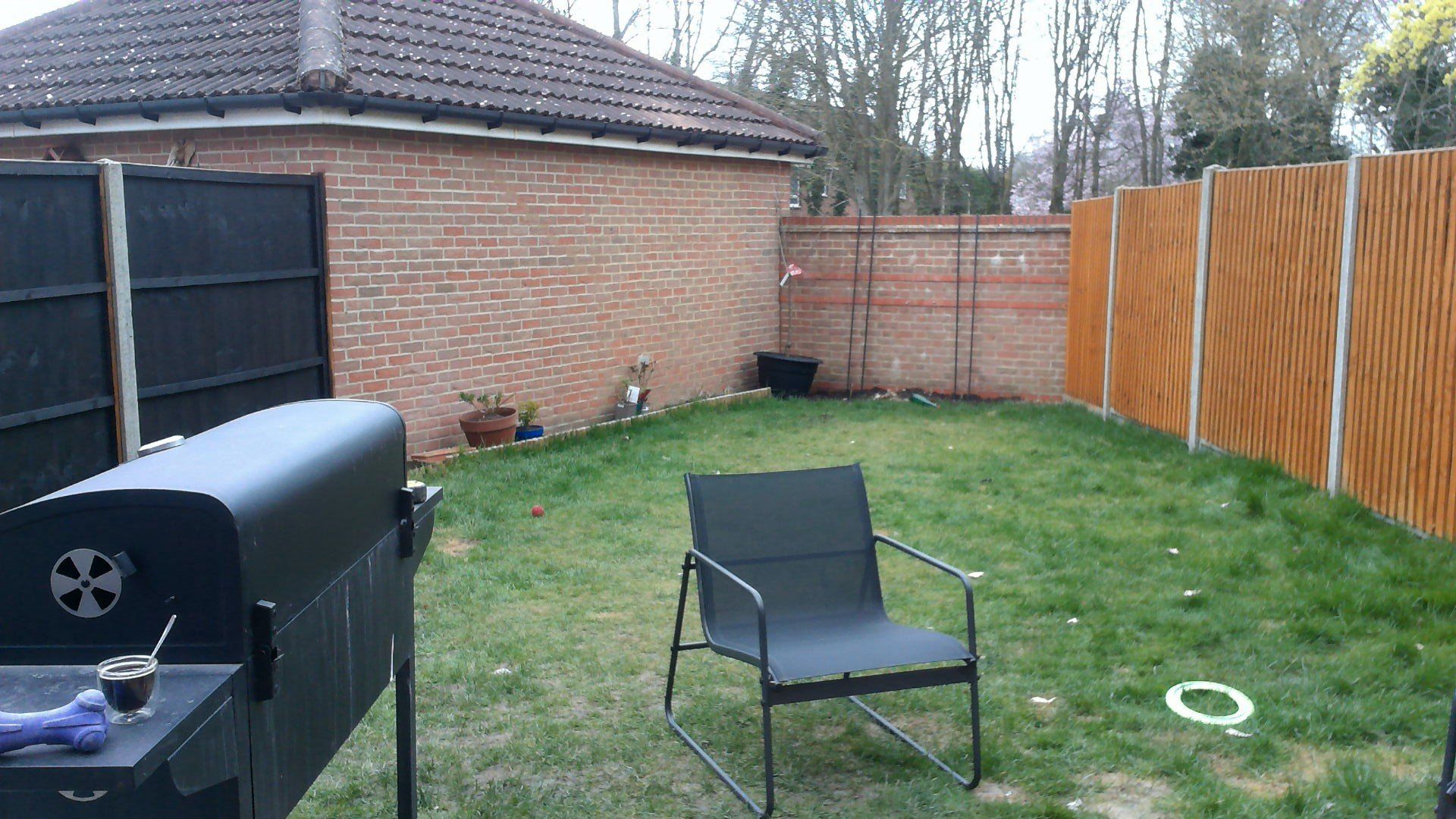 There is a chair and a grill in the backyard.