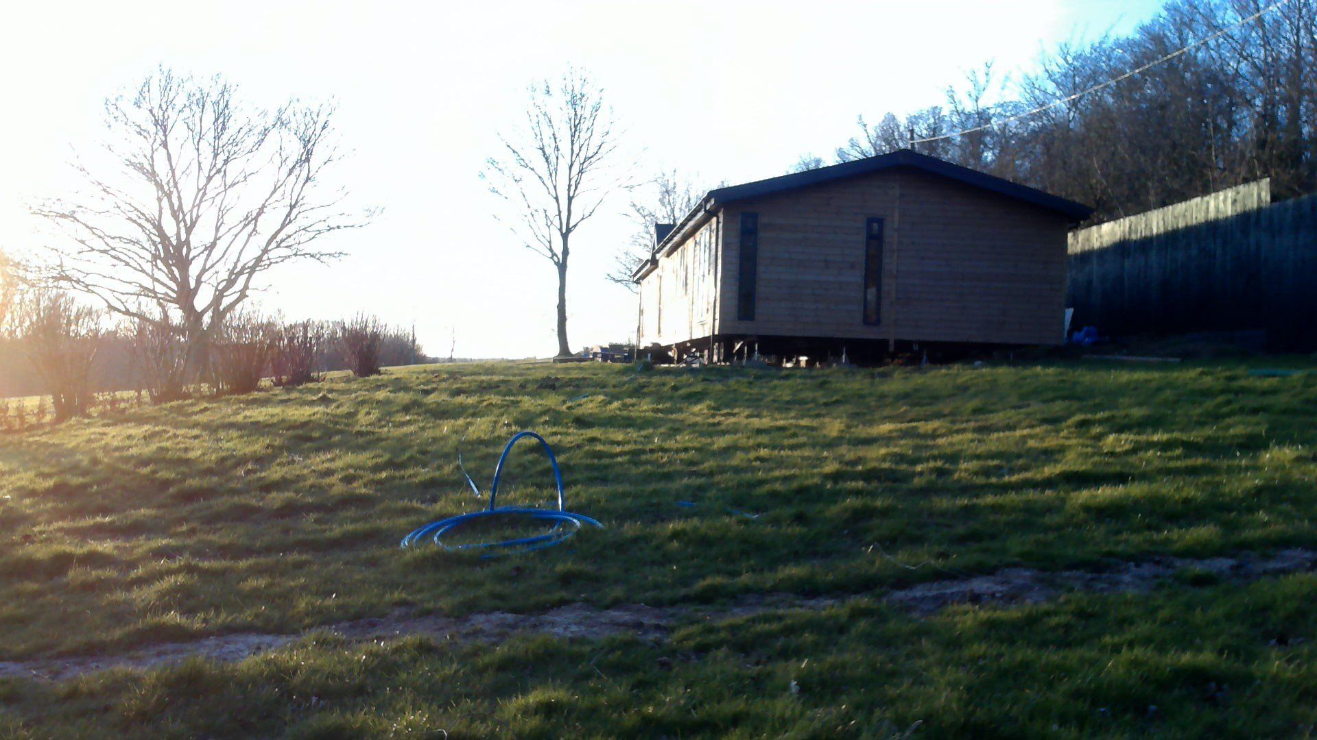 A small house is sitting on top of a grassy hill.