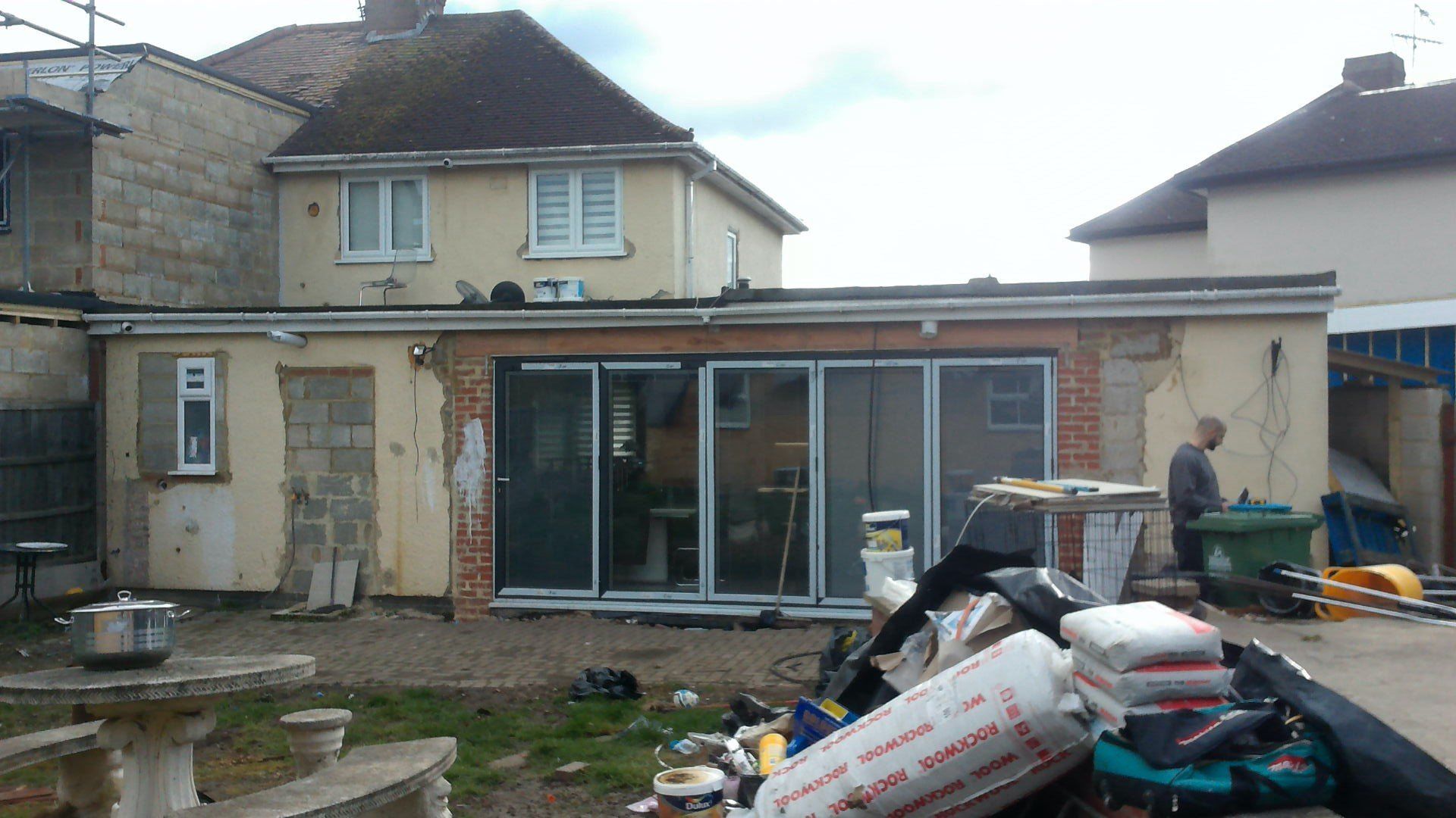 A man is standing in front of a house that is being remodeled.