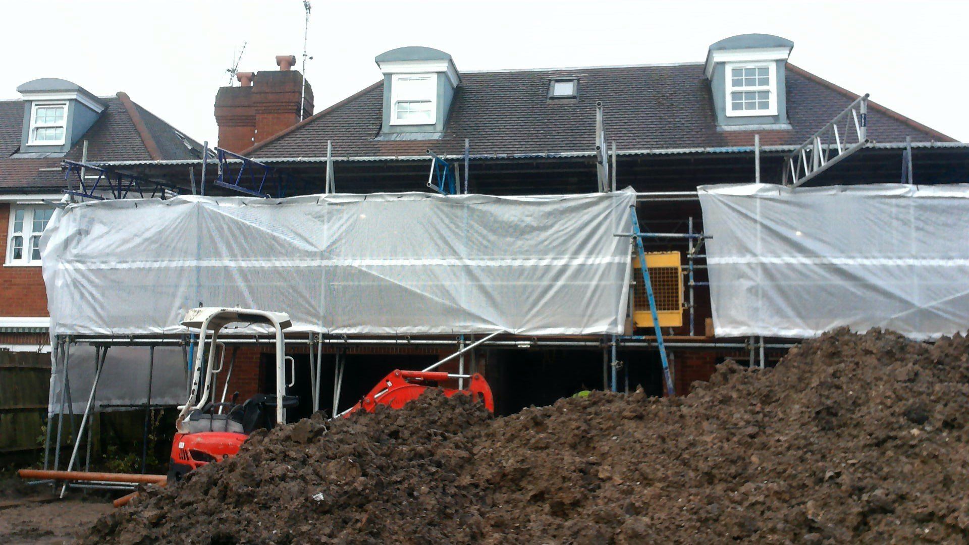 A large pile of dirt is in front of a house under construction