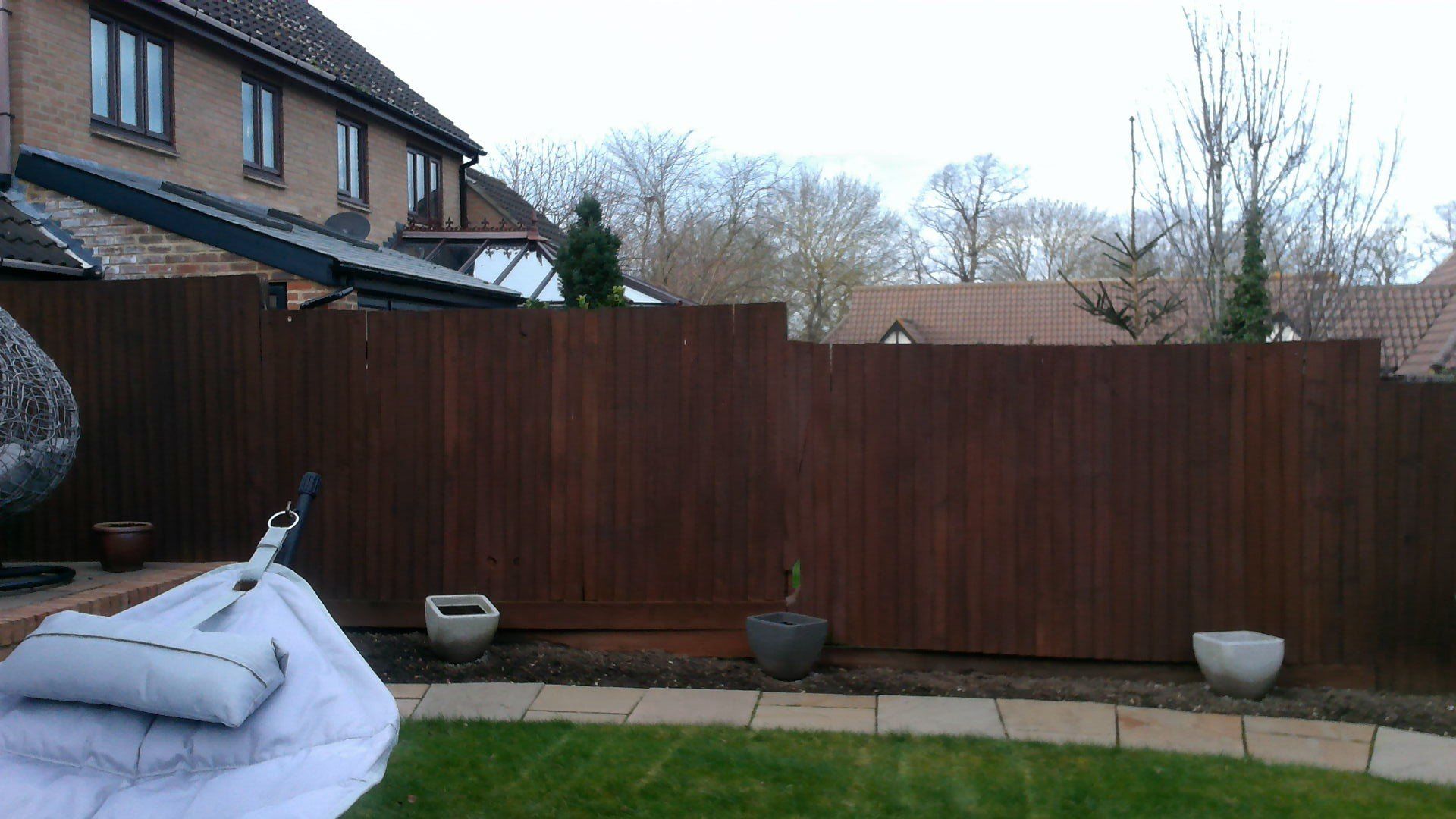 A wooden fence in a backyard with a house in the background