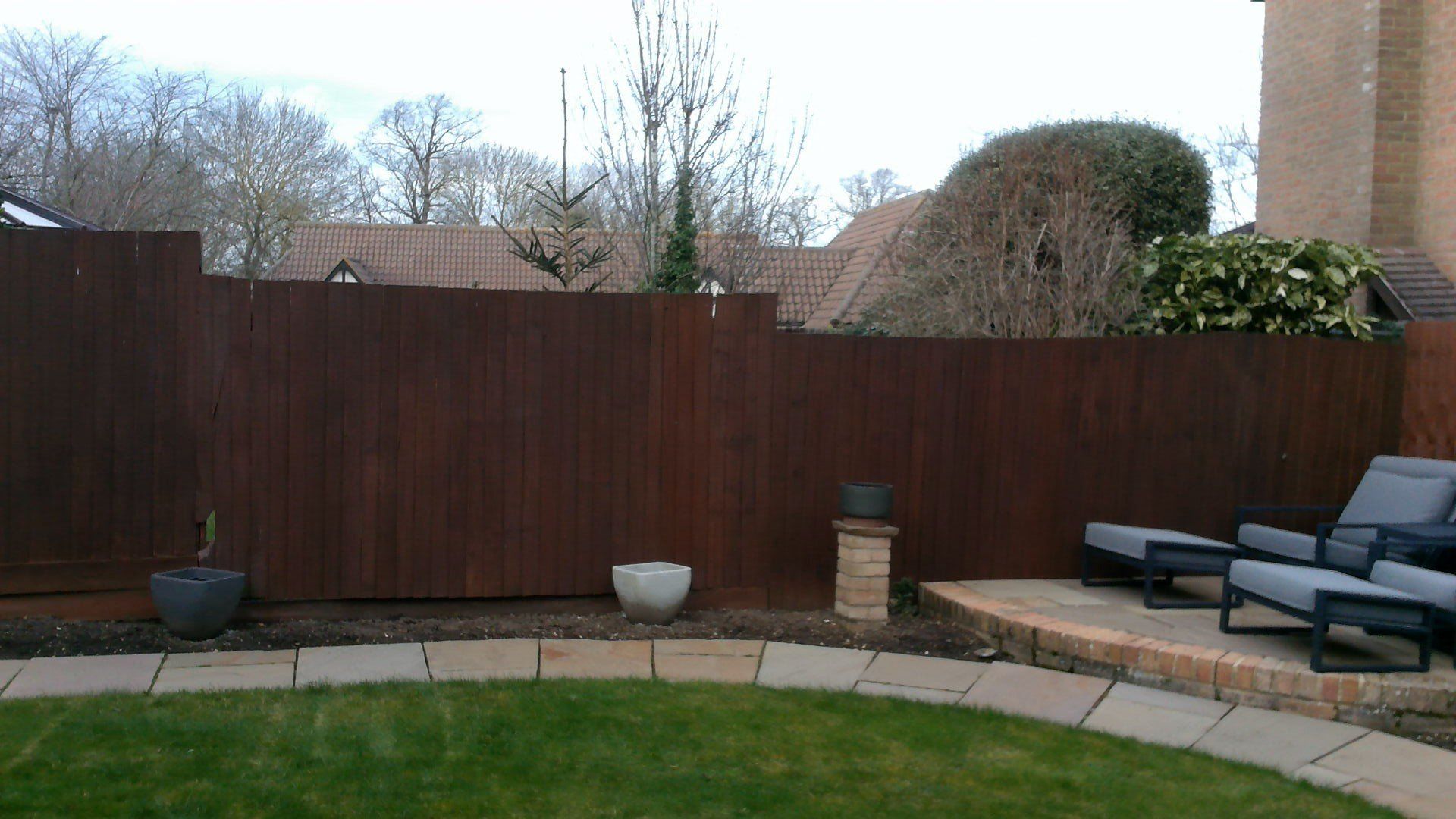 A backyard with a wooden fence and chairs