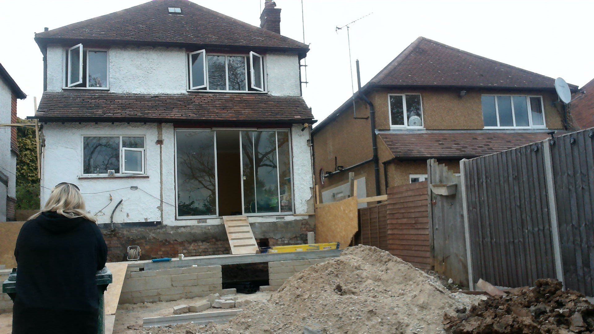 A woman is standing in front of a house that is under construction