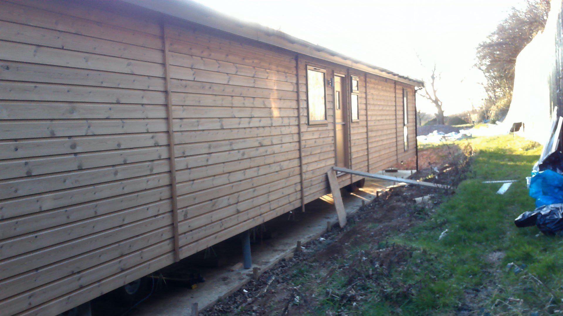 A person is standing in front of a wooden building.