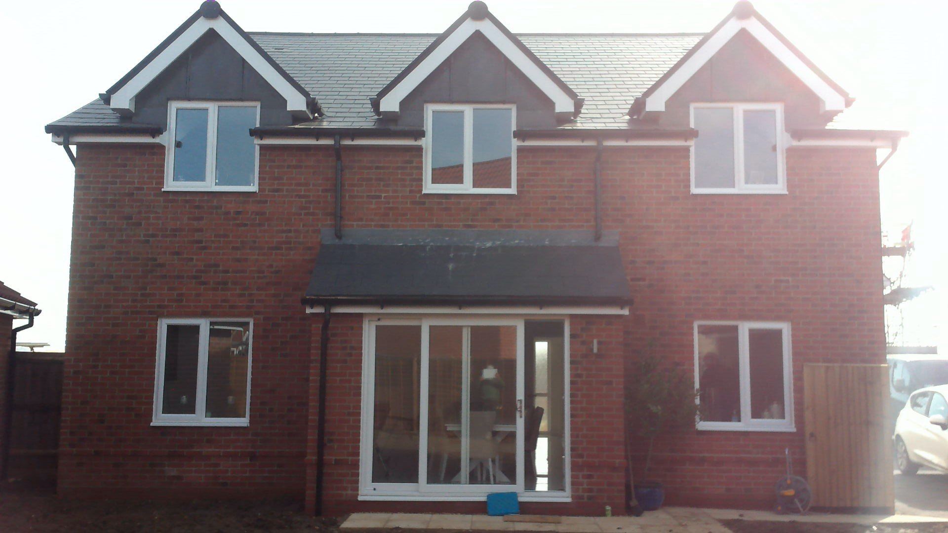 A red brick house with white windows and a black roof