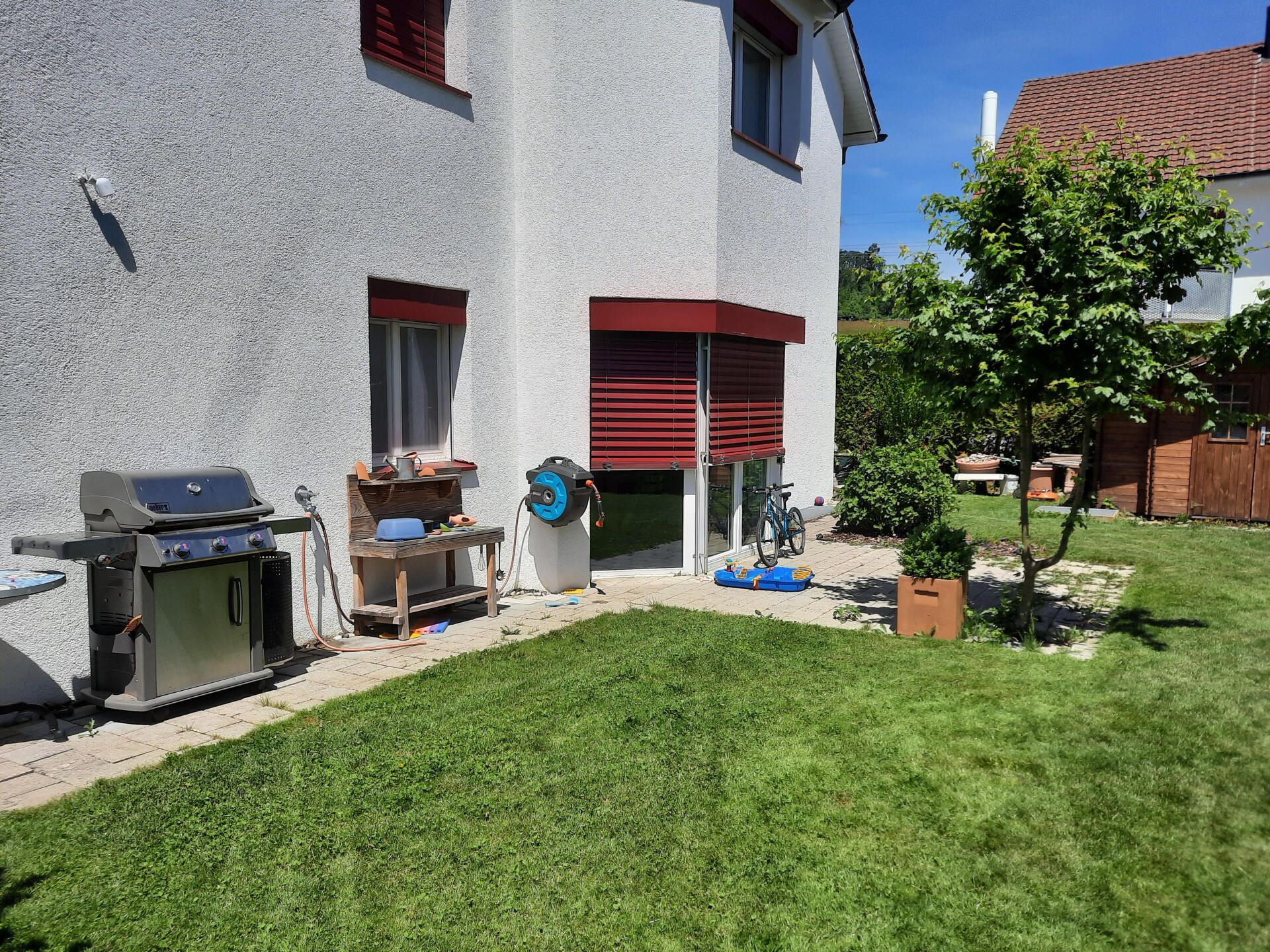 There is a grill in the backyard of a house.