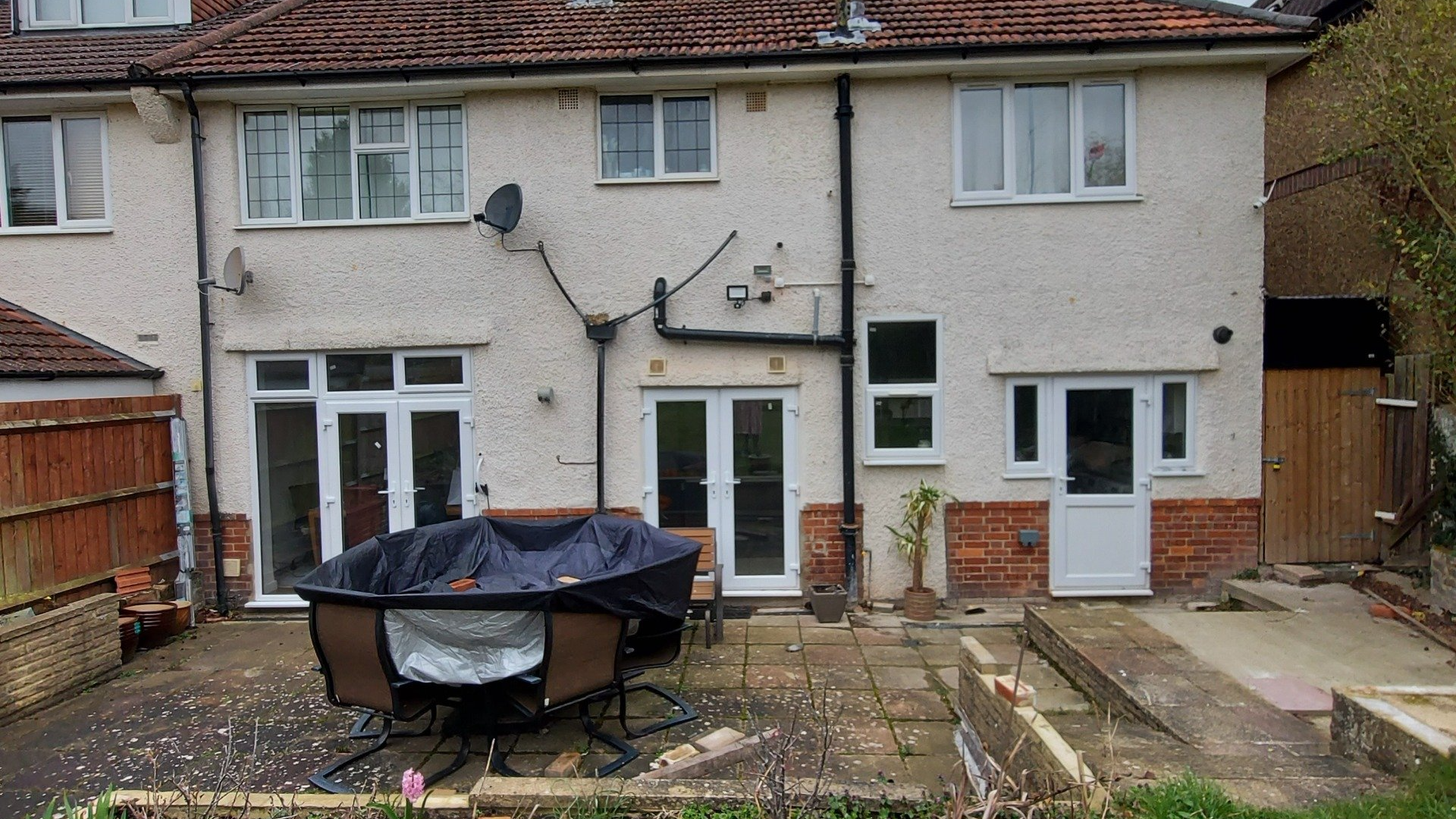 The back of a house with a patio and a satellite dish on the roof.