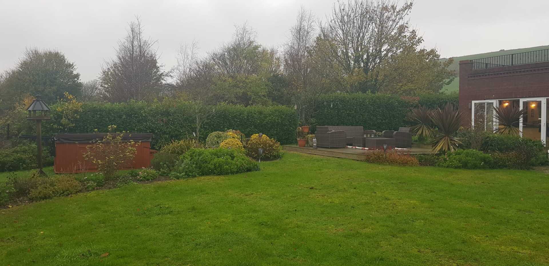 A large lush green lawn in front of a house on a cloudy day.