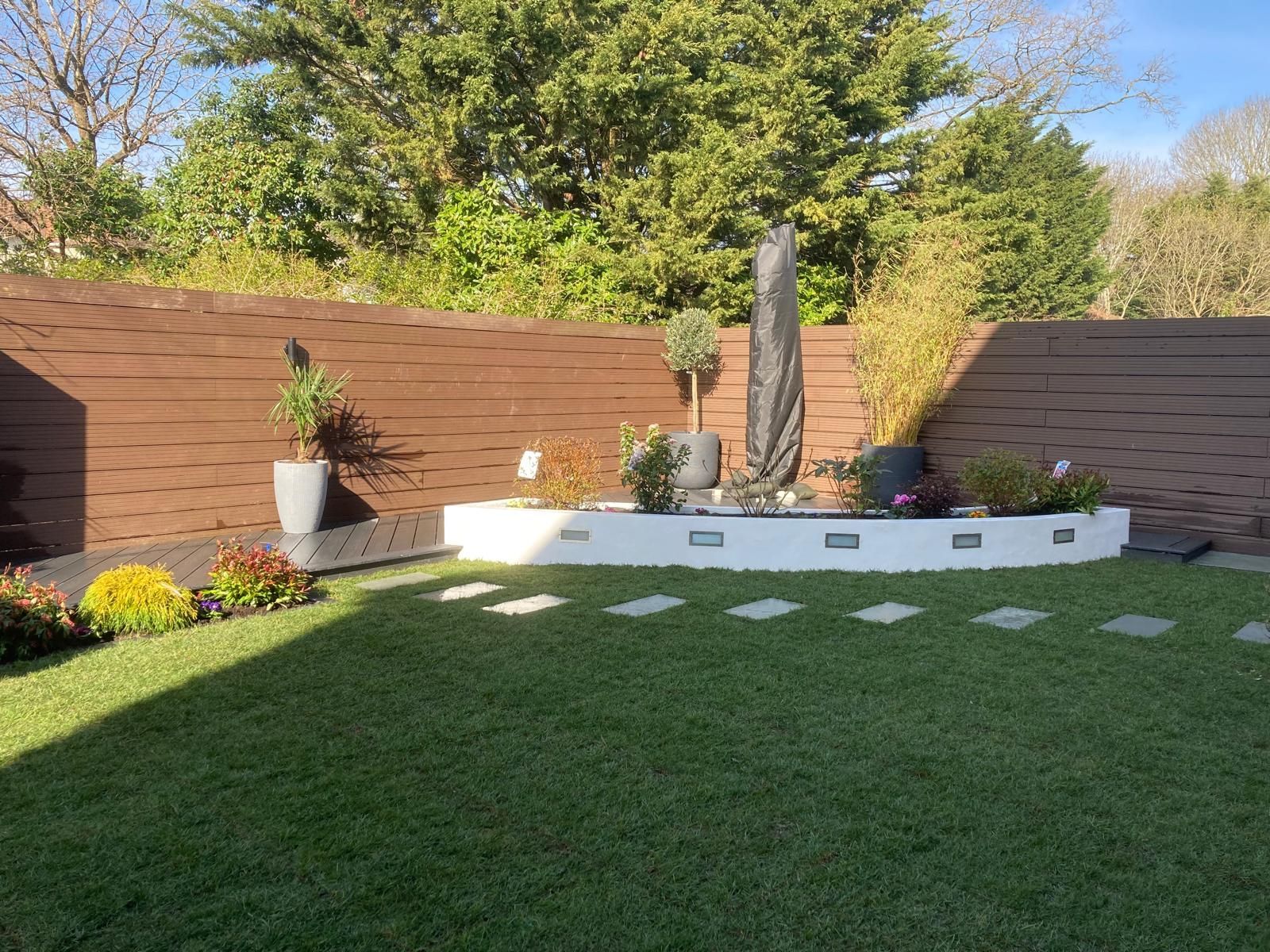 A well-manicured backyard with a water feature, lawn, and a modern brown wooden fence.